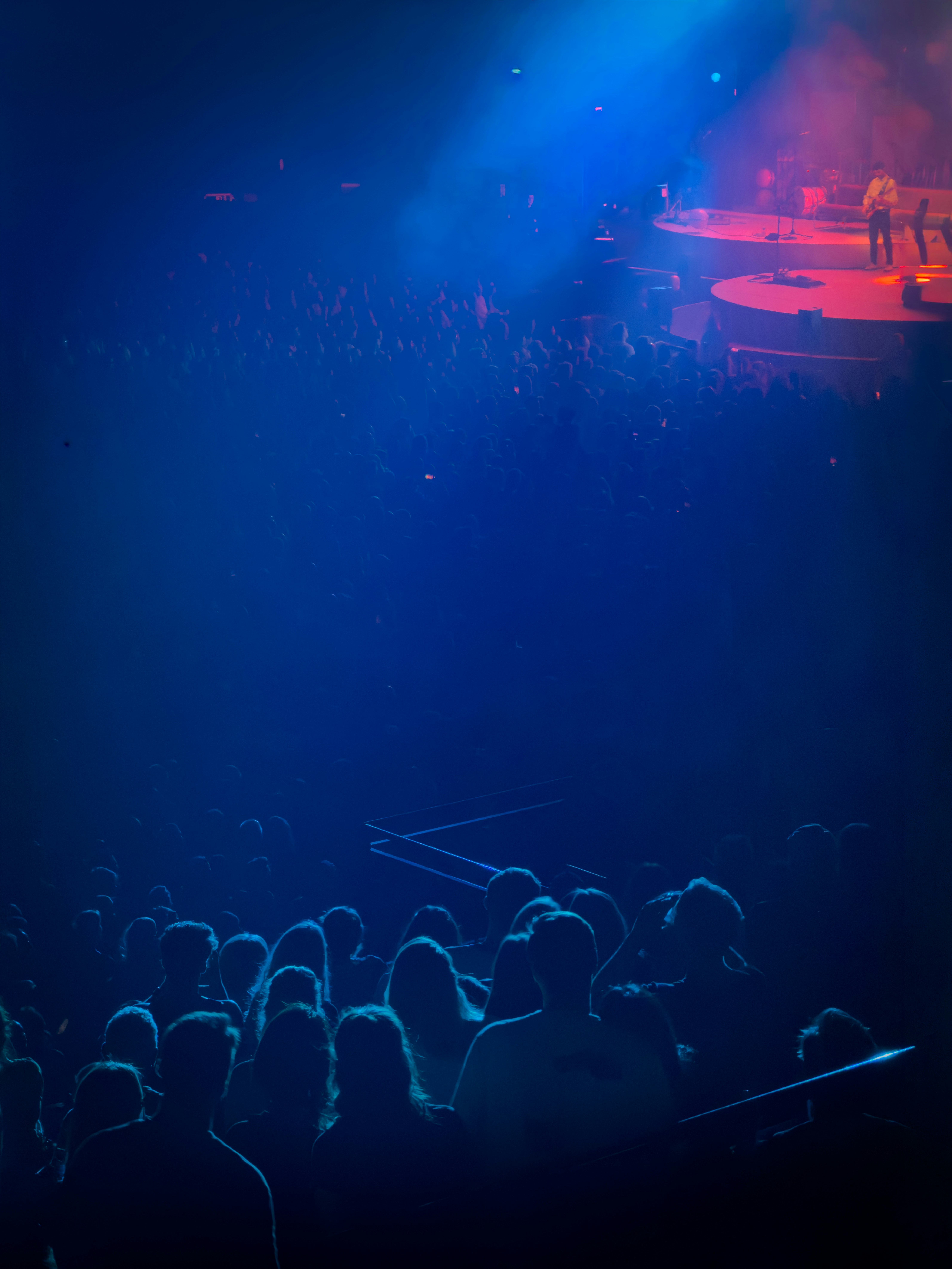 A crowd of people in a dark concert hall watching a stage performance