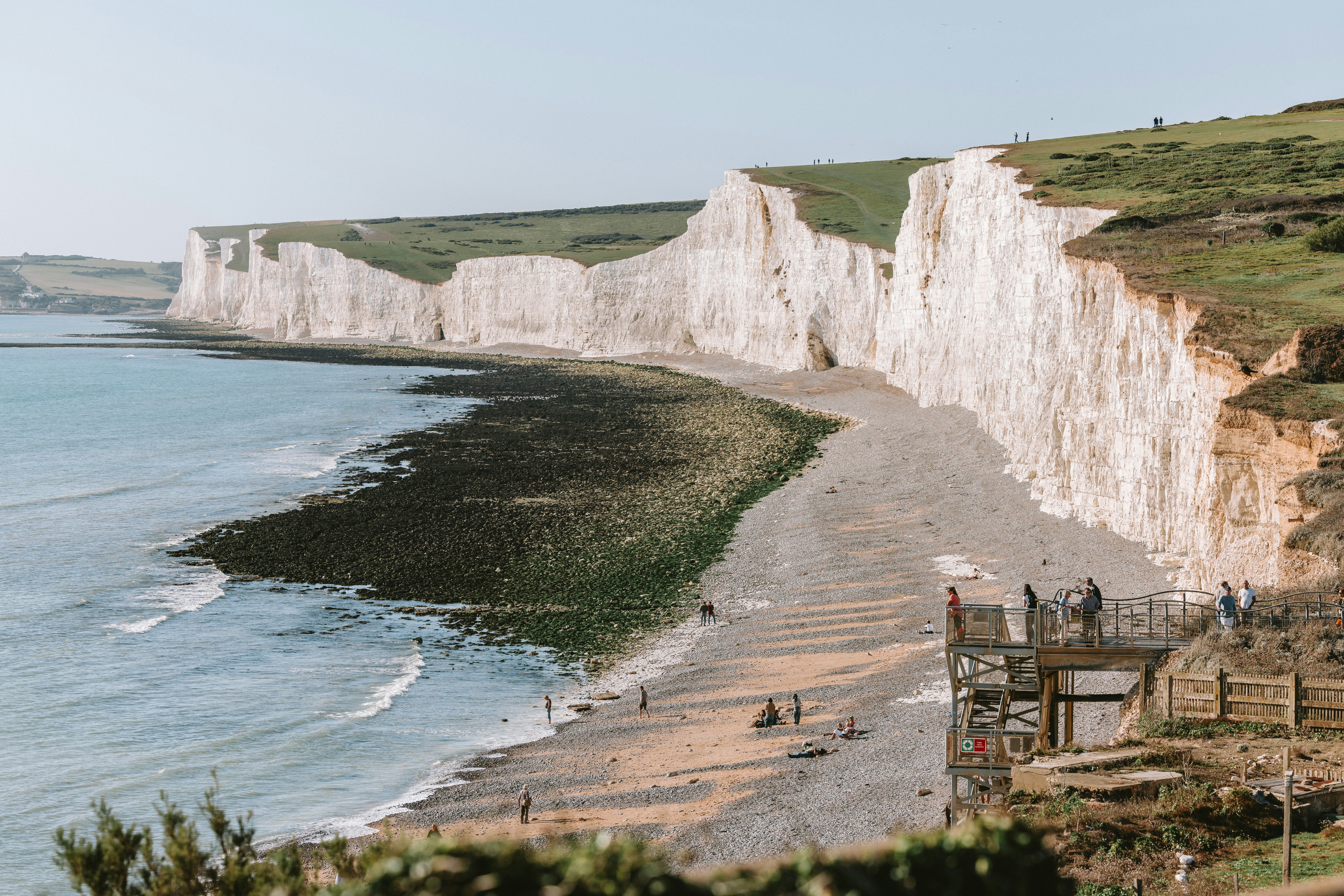 People on a pebble beach below the white chalk cliffs of Seven Sisters