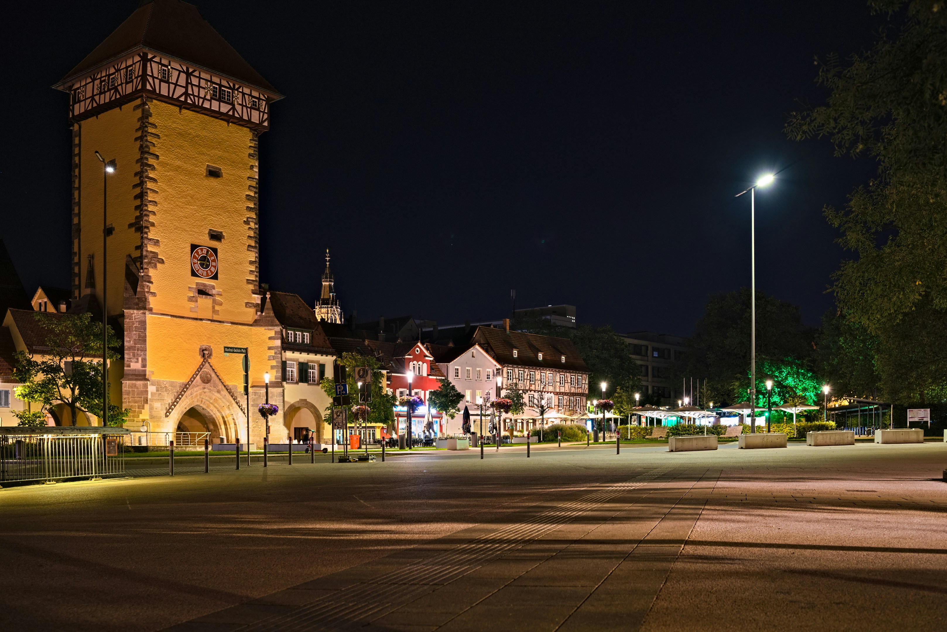 A tall yellow medieval tower with timber framing at night in Heilbronn