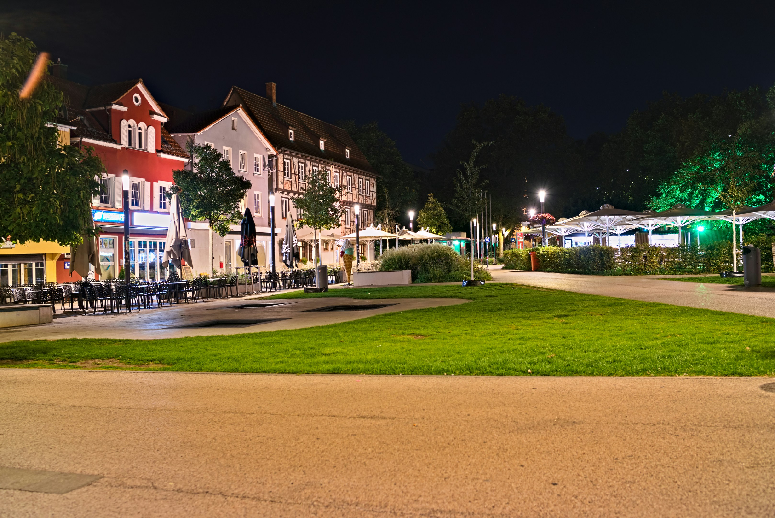 A town square with half-timbered buildings and outdoor cafe seating at night