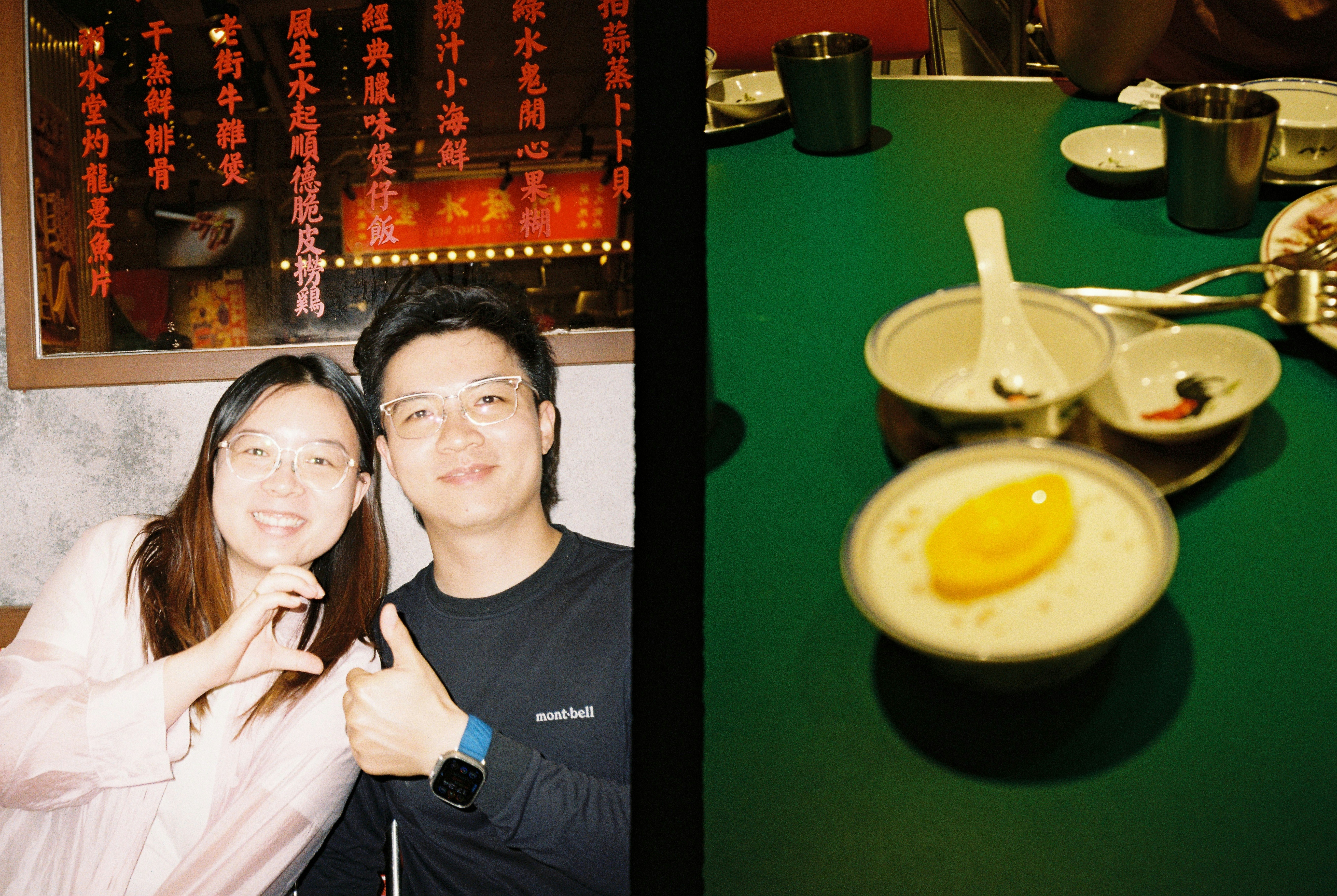 A woman and a man smiling at a table with a dessert bowl