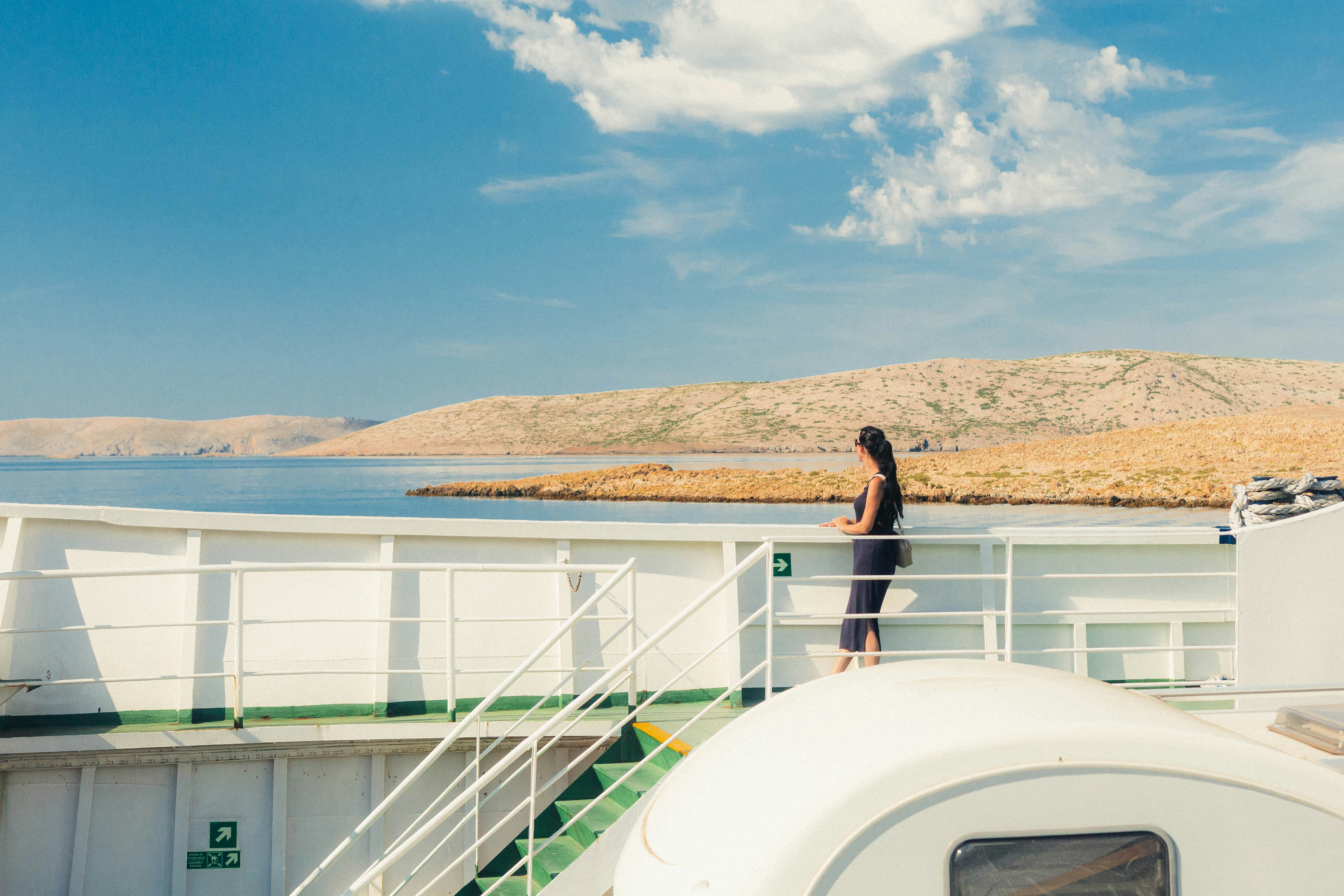 A woman in a dark dress leaning on the railing of a ferry