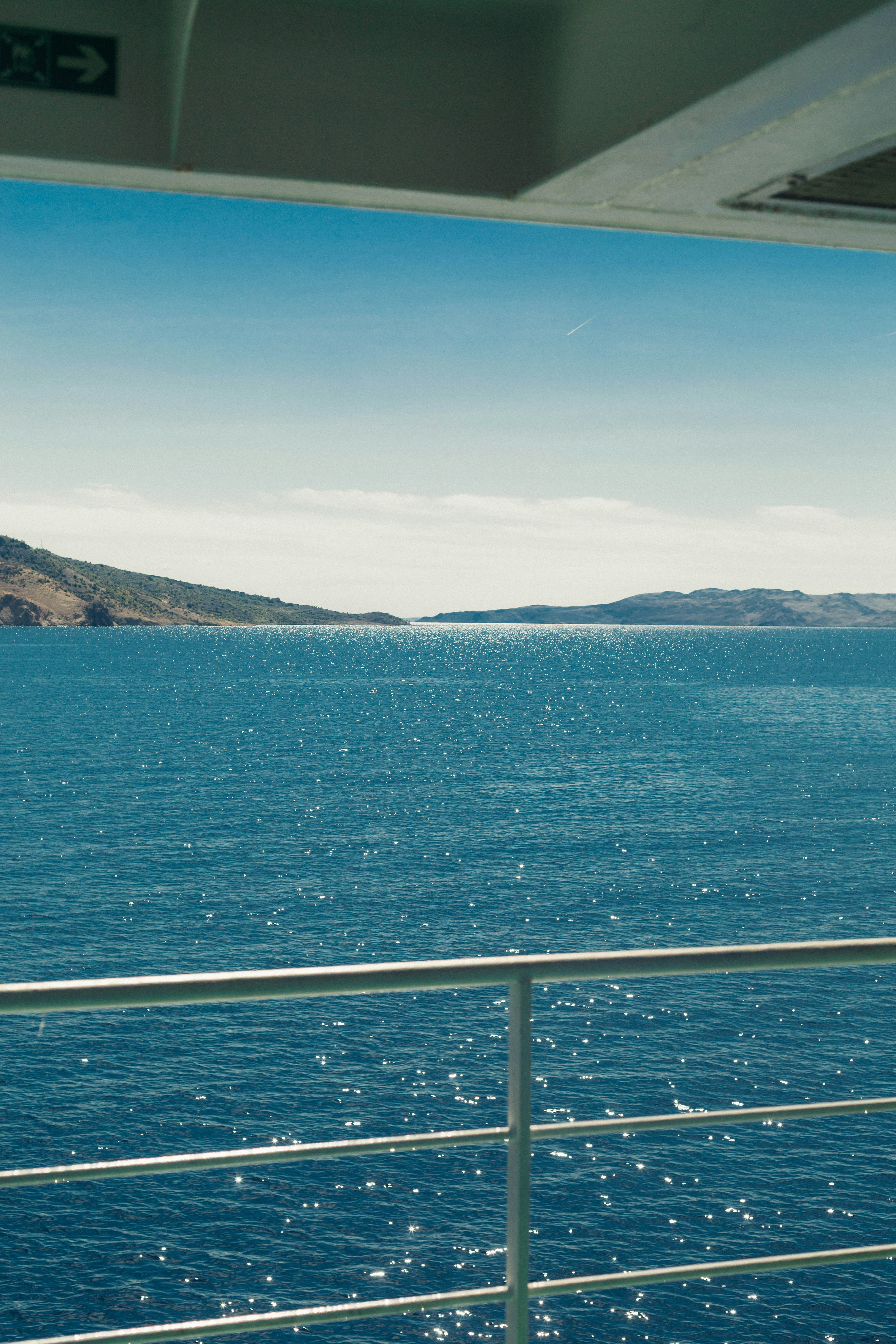 A view of sparkling blue sea and distant hills from a ship deck
