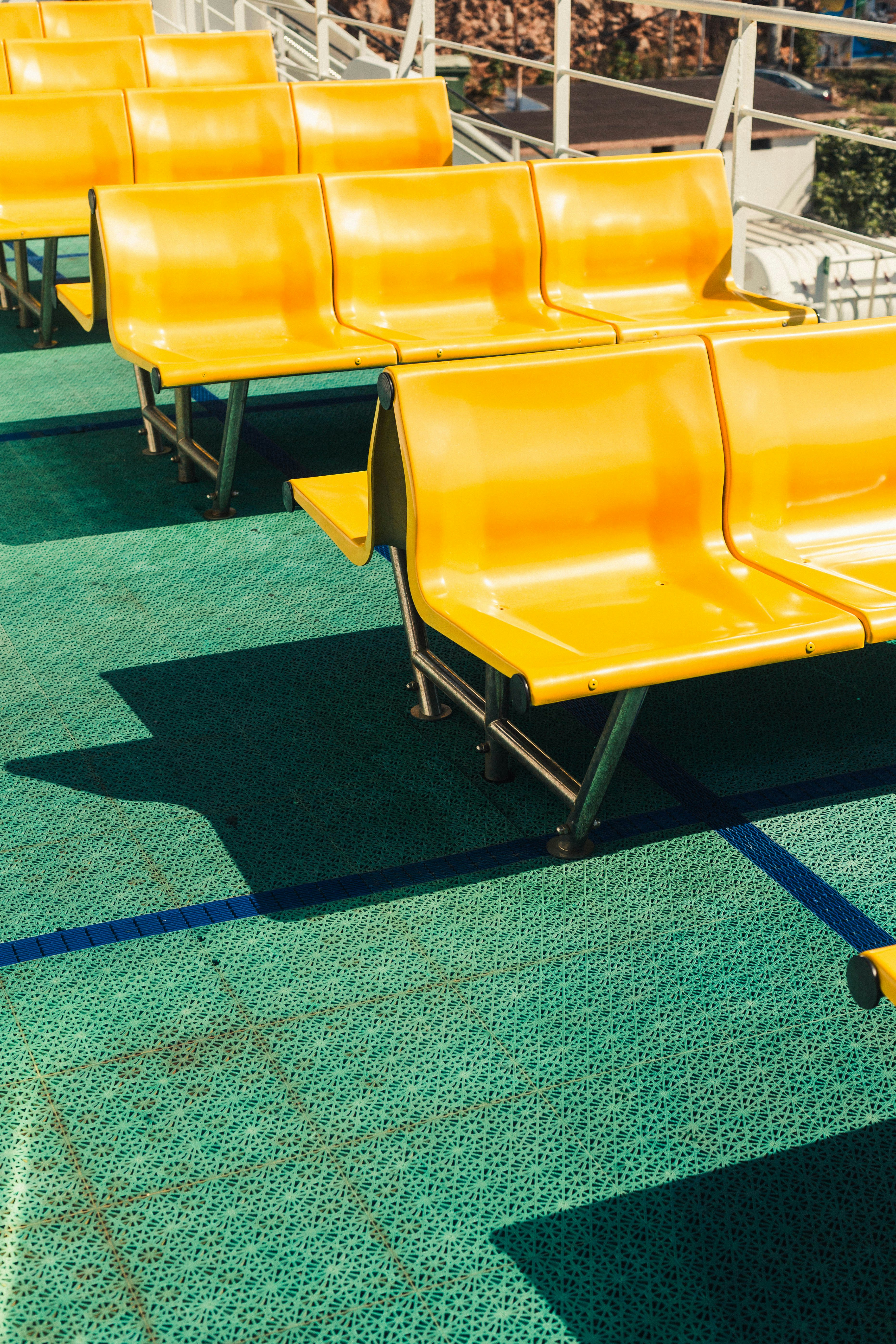 Rows of bright yellow plastic chairs on a textured green deck