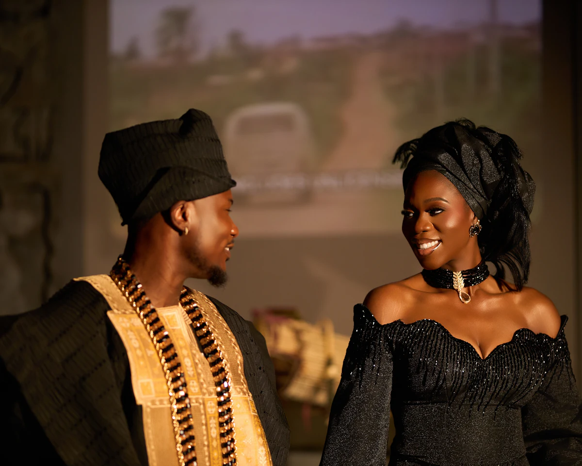 A couple in black traditional attire looking at each other