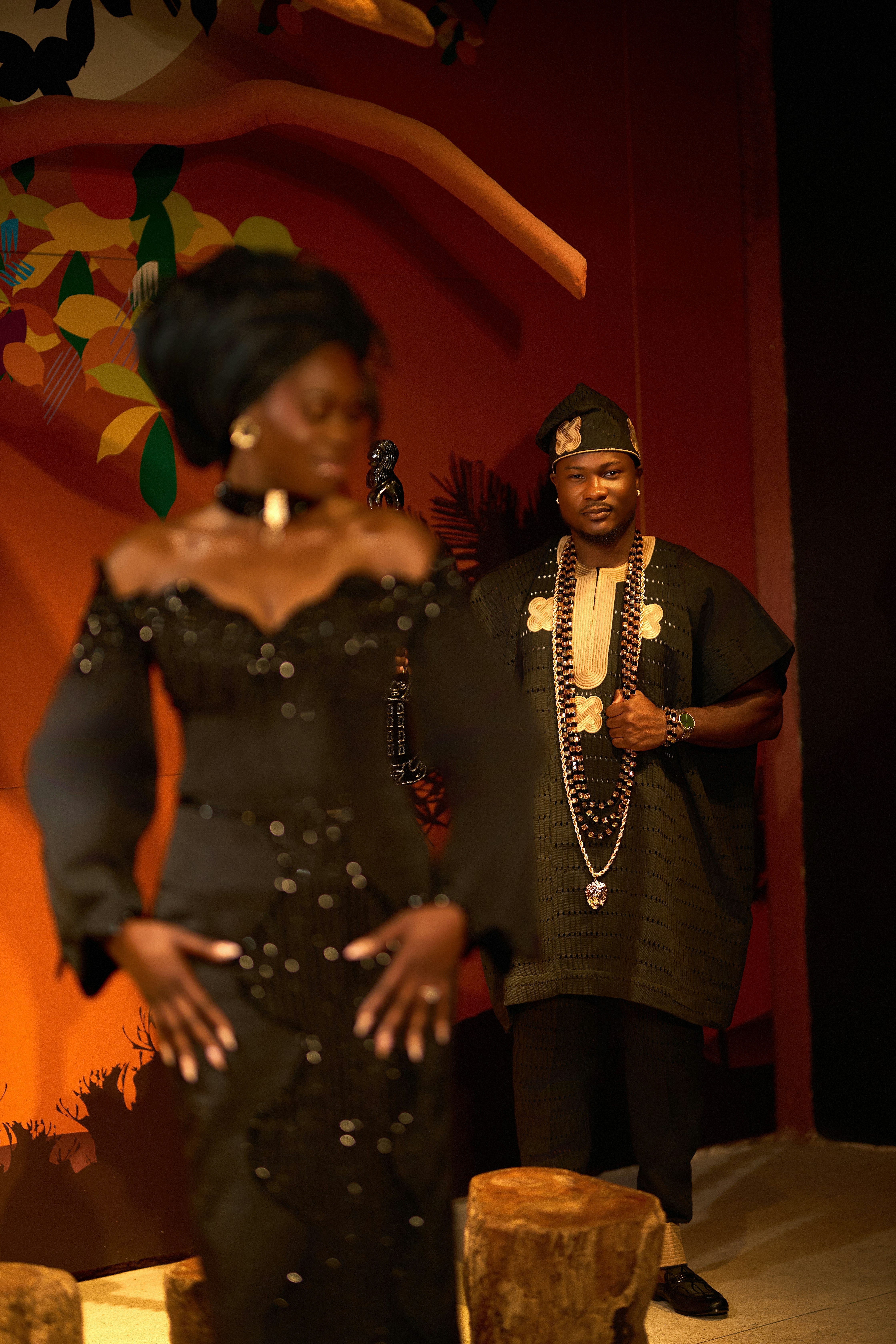 A man in a black traditional tunic and cap standing behind a woman