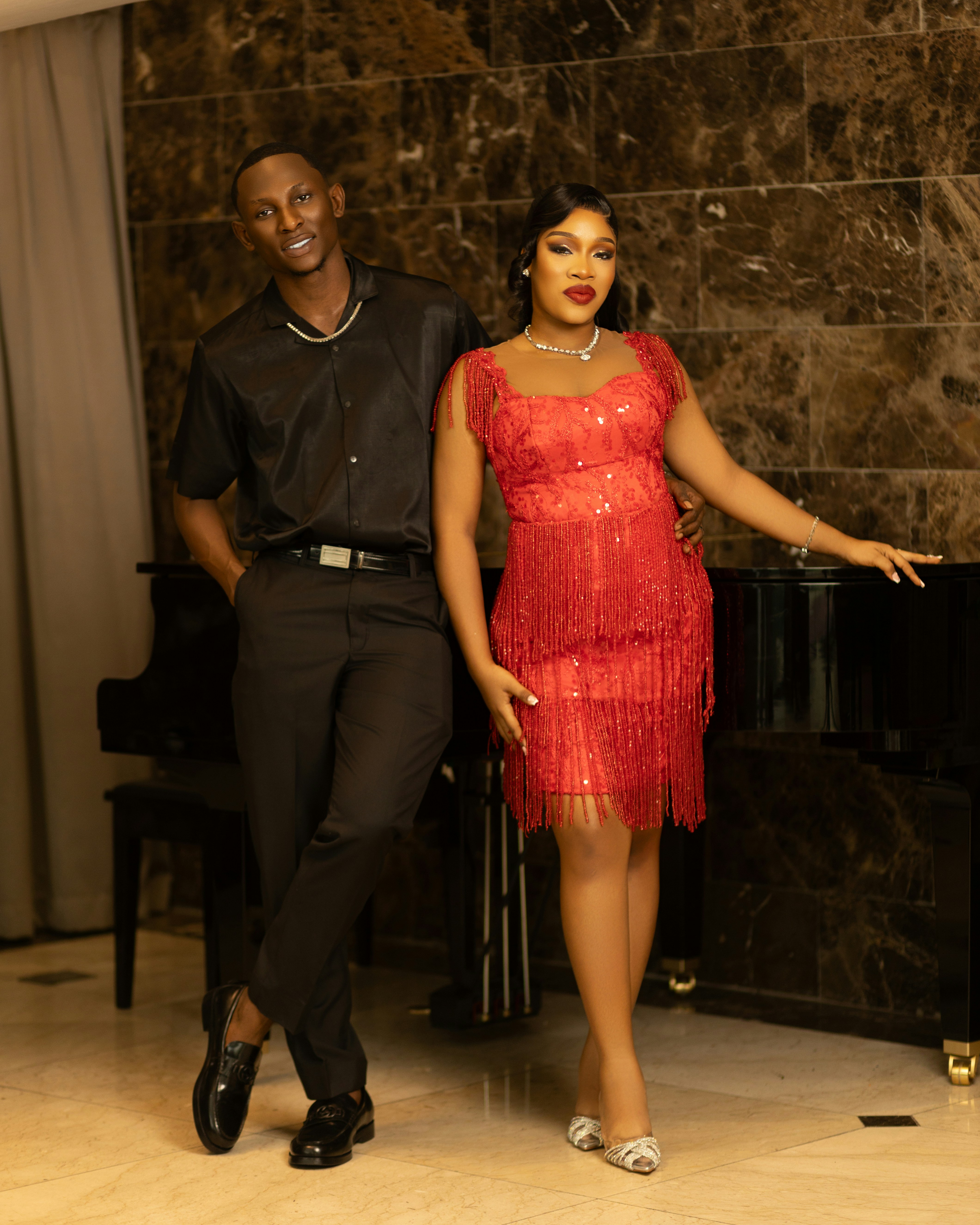 A man in a black shirt and a woman in a red fringe dress