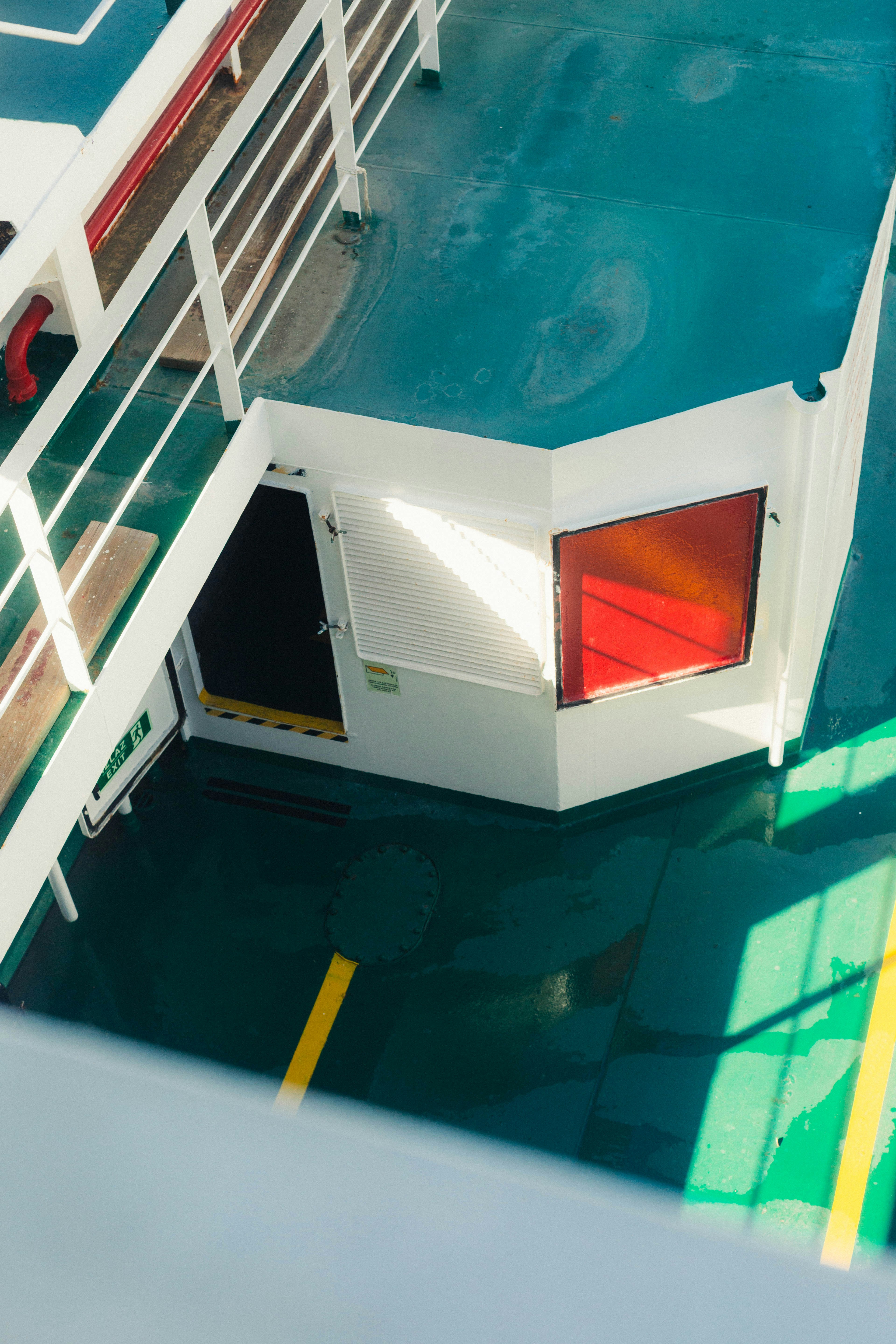 A white ship deck with green flooring and a red window frame