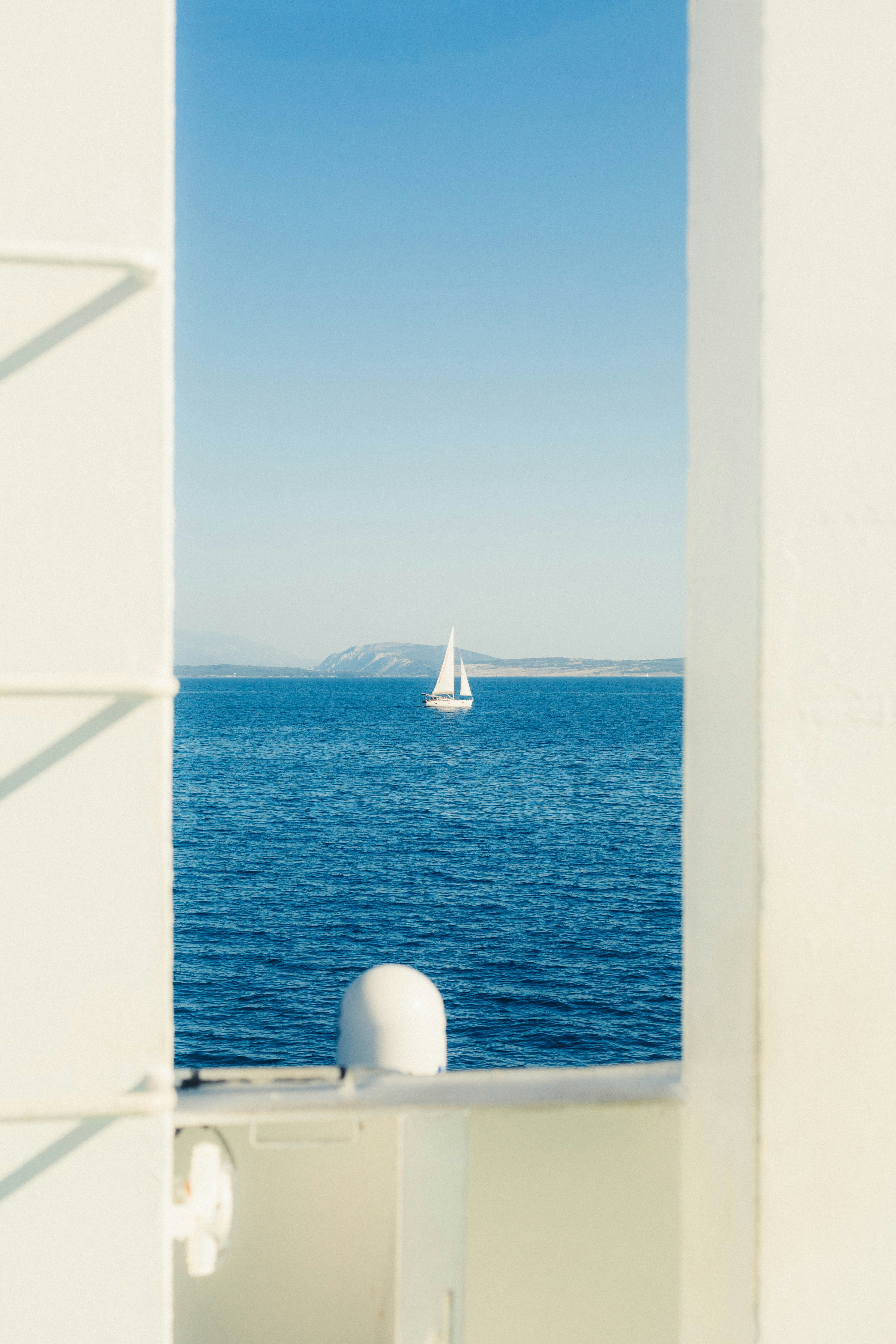 A white sailboat on blue water viewed through a vertical frame