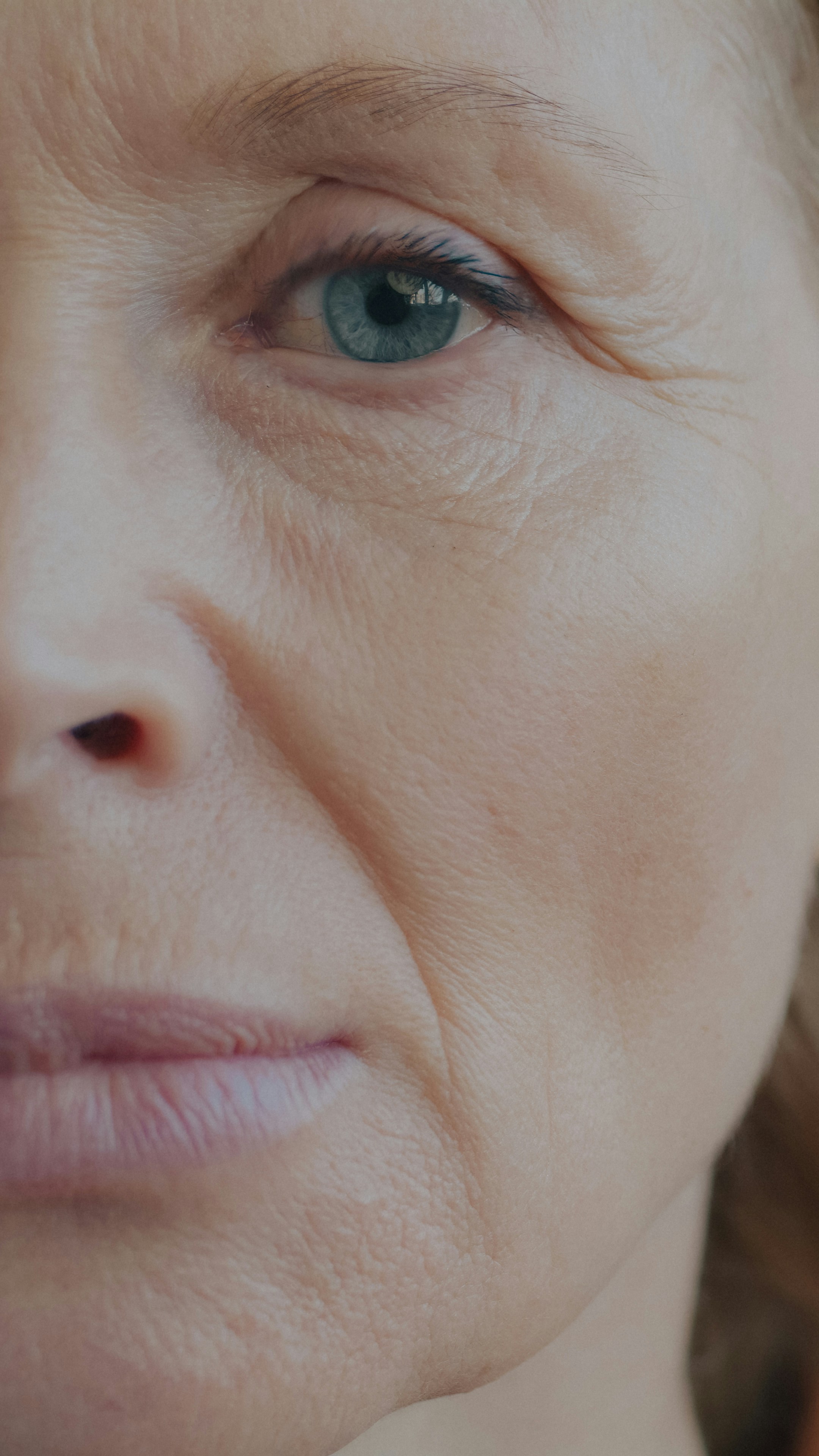 A close-up of a woman with blue eyes and visible skin texture