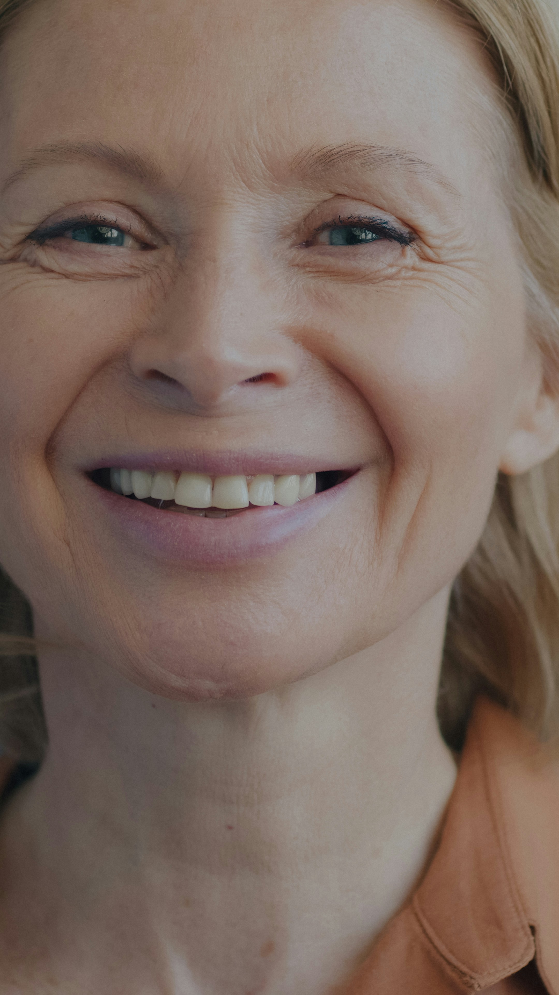 A close-up of a smiling woman with blonde hair and light eyes