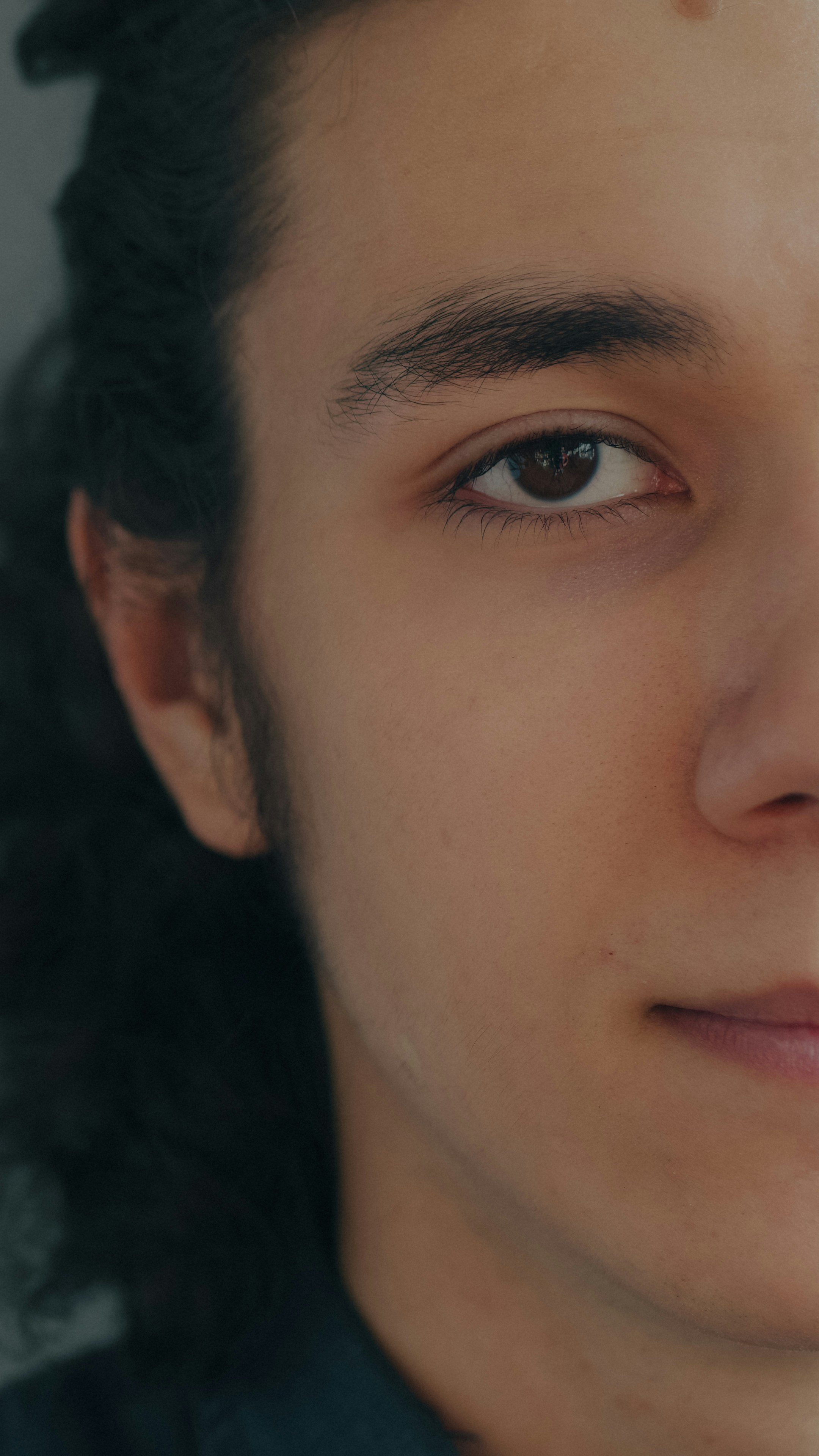 Un primo piano di una persona con capelli scuri e ricci e occhi marroni