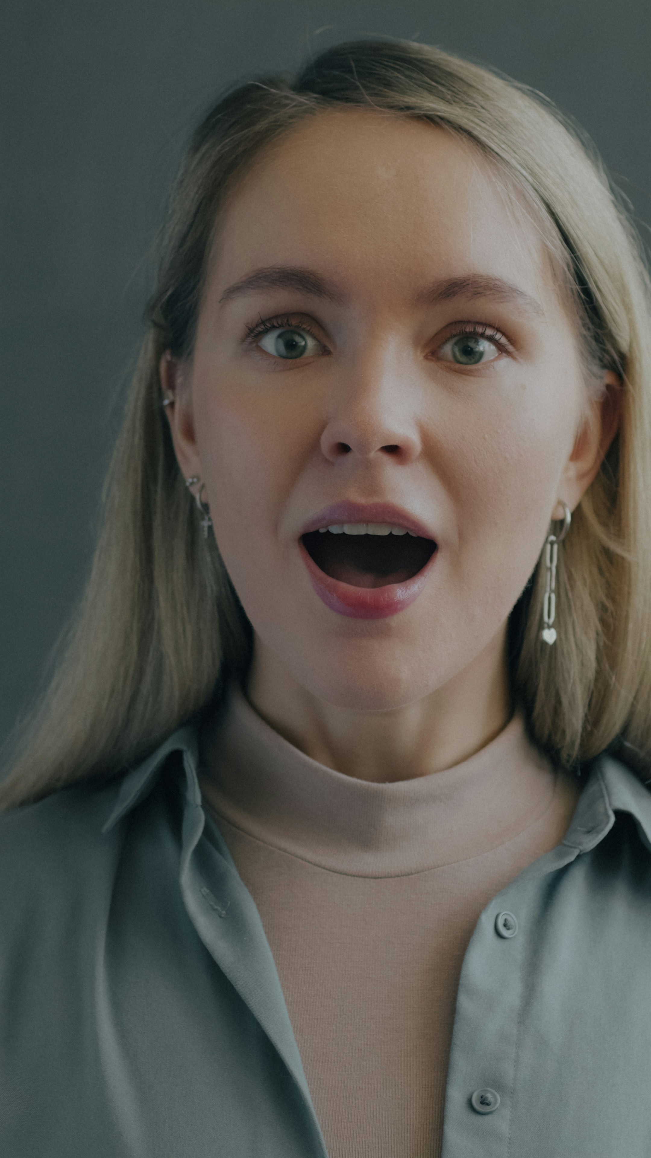 Slow motion portrait of excited young lady looking at camera enjoying good surprise on black studio background. People and positive emotion concept.