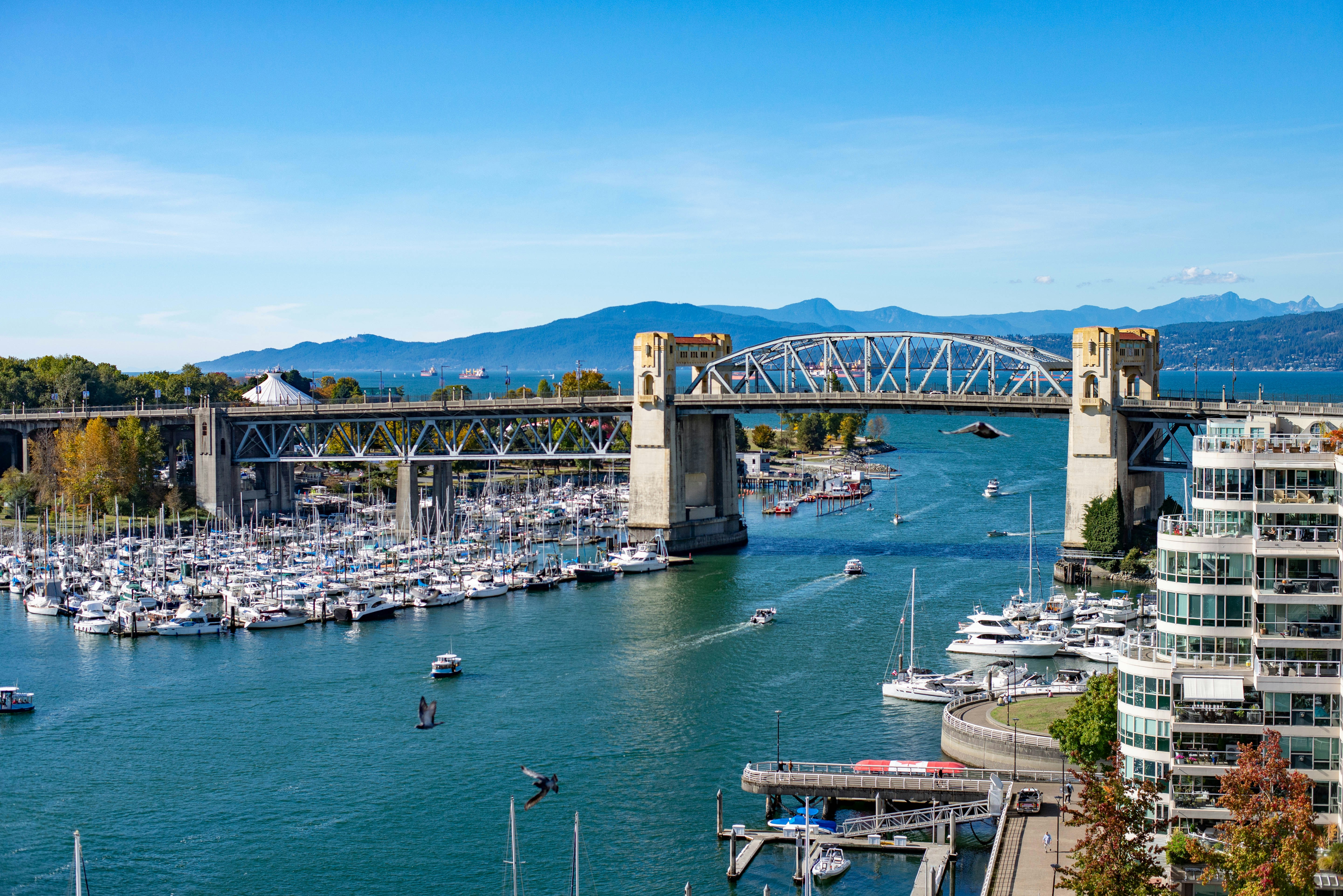 Burrard Street Bridge over False Creek with a marina and mountains in Vancouver