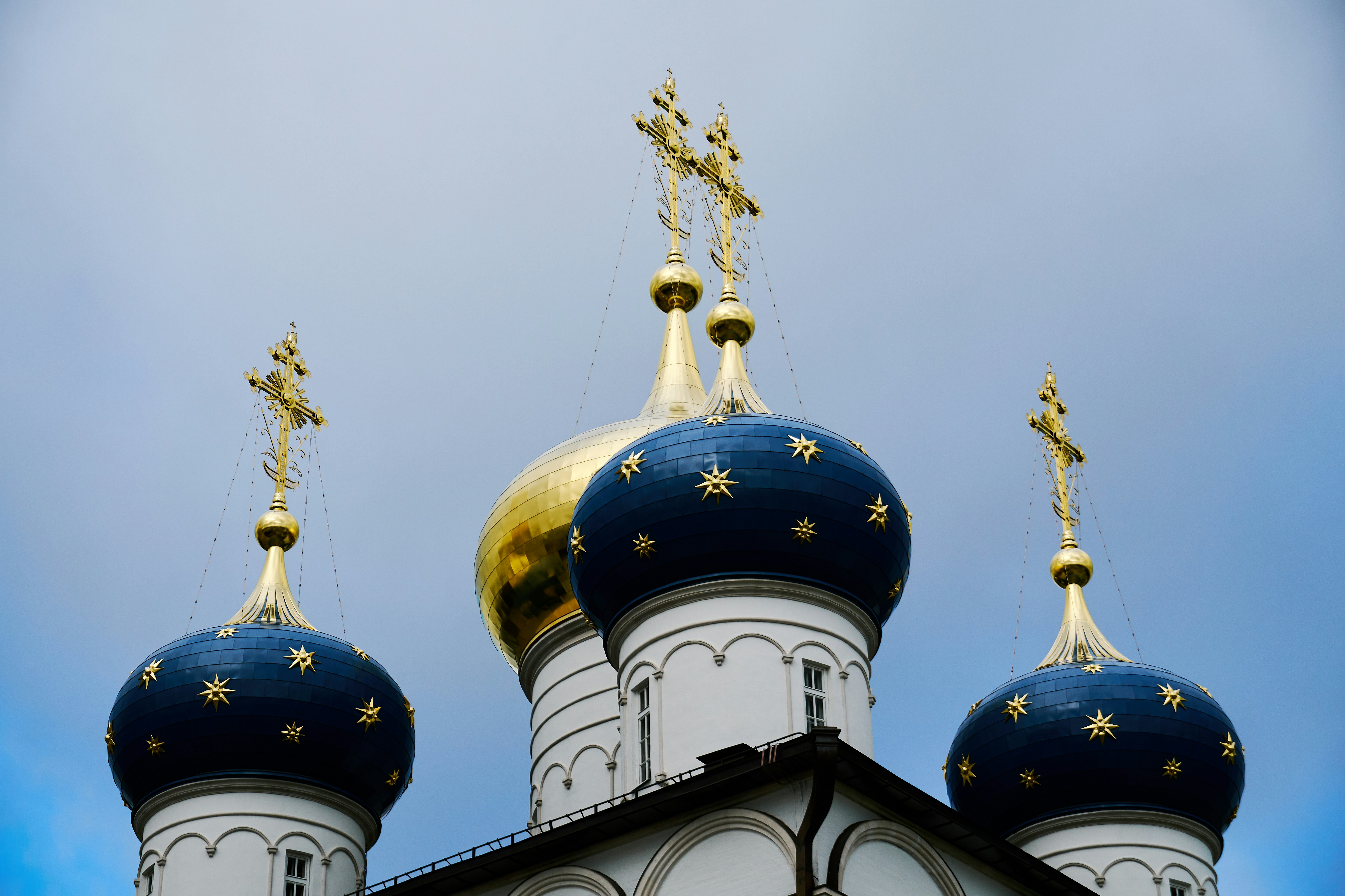 Blue onion domes with gold stars and crosses against a pale blue sky
