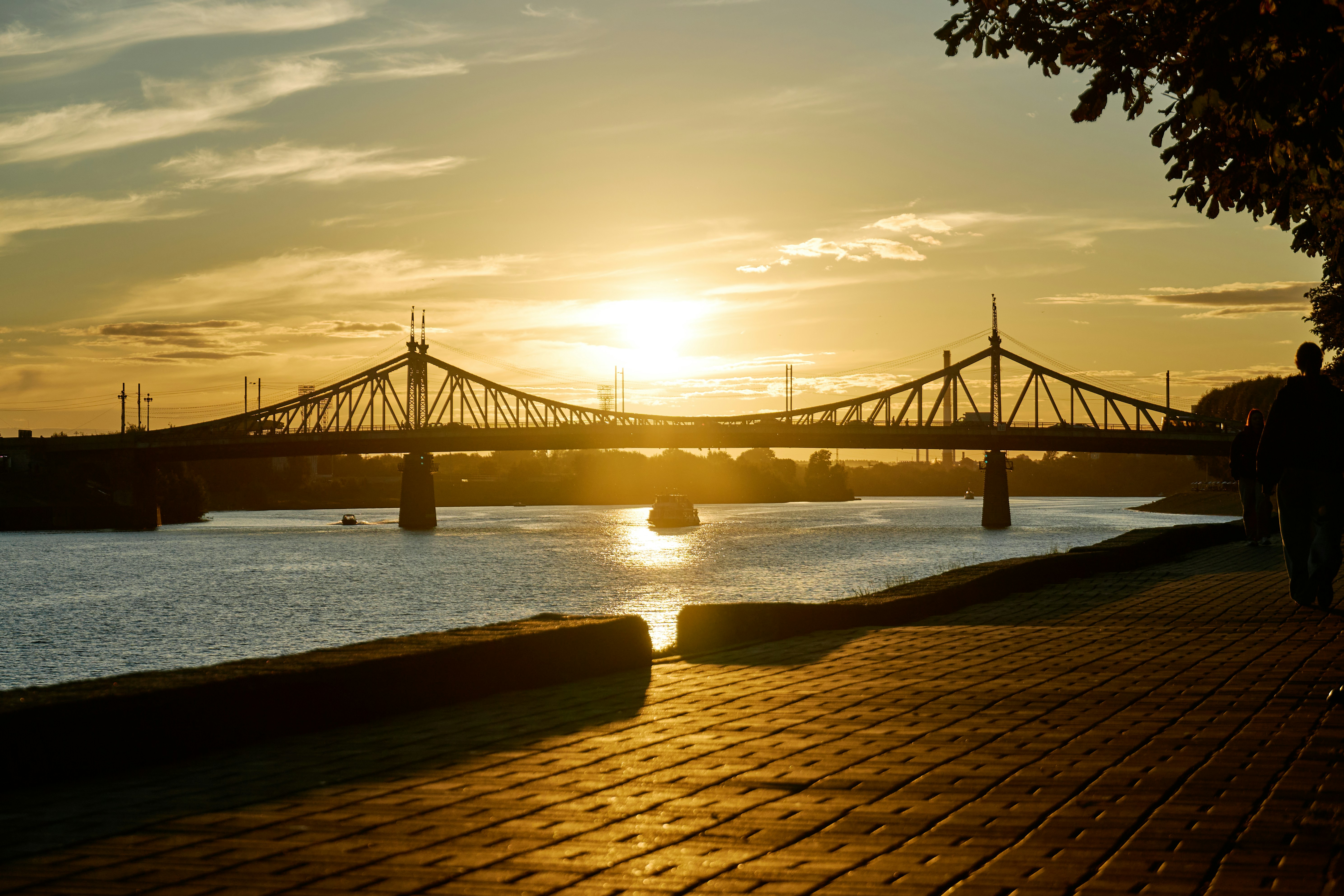 A bridge over a river during golden hour with a person walking nearby