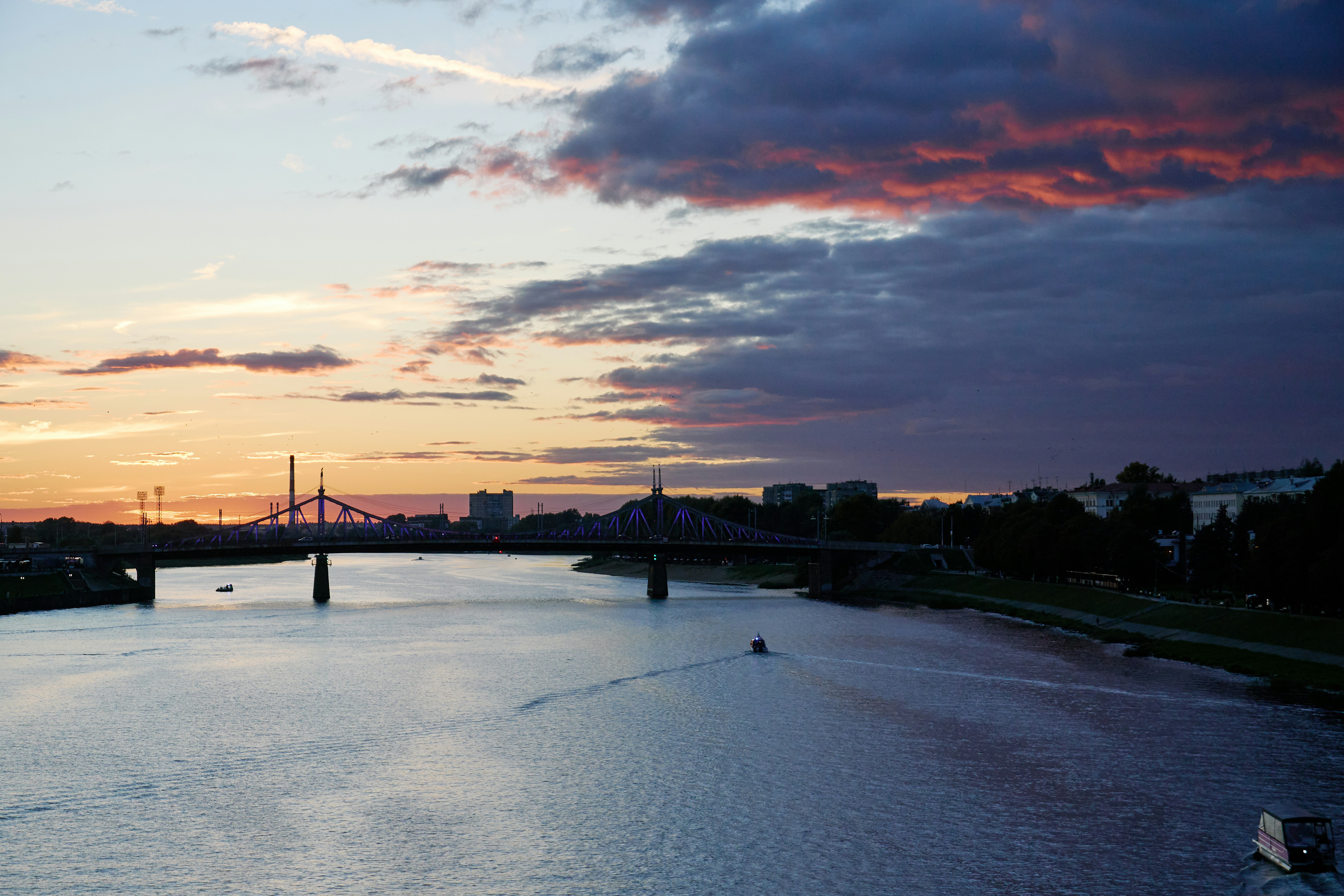 A bridge over a wide river under a sky with purple and orange clouds