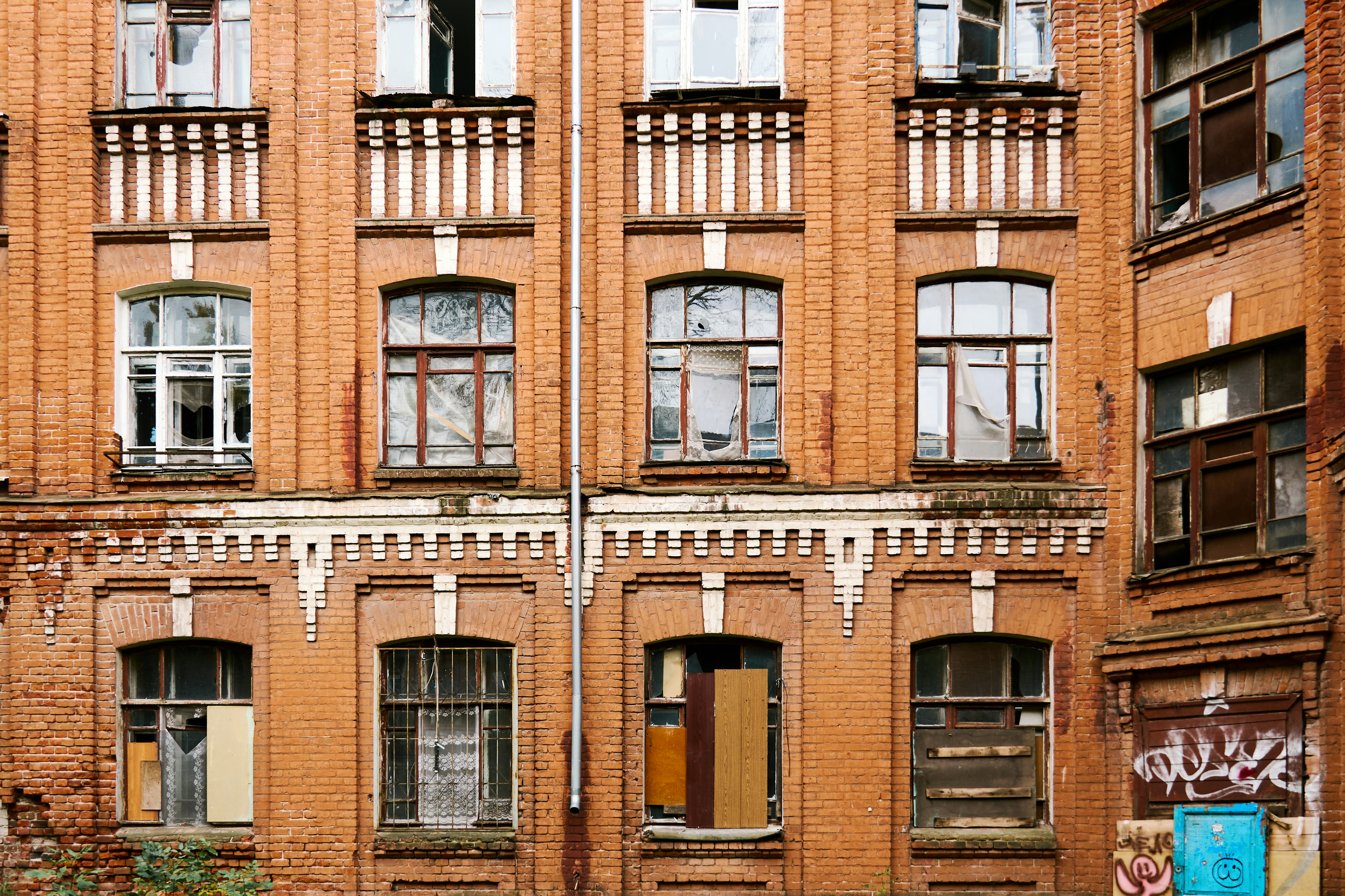 A weathered red brick building facade with multiple windows and decorative white masonry