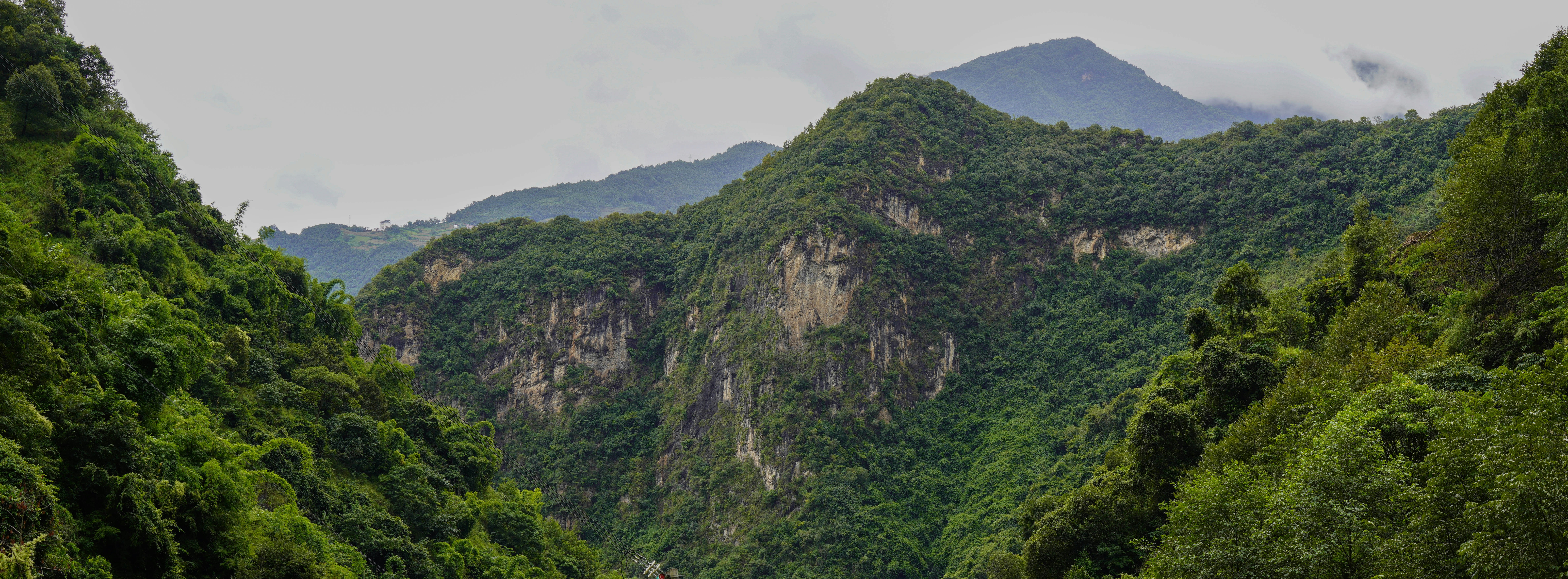 Lush green mountains with rocky cliffs under a cloudy sky