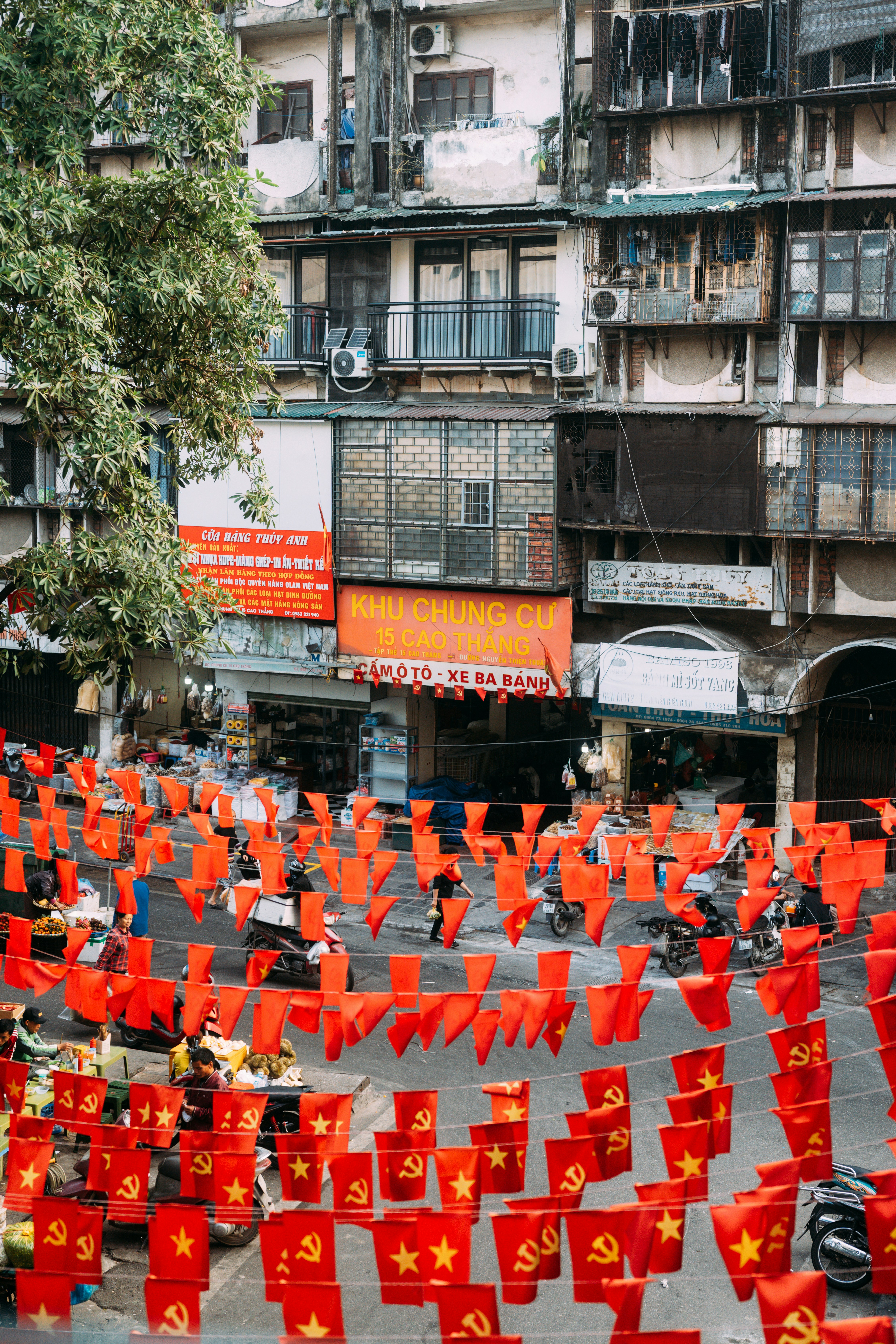 Red flags with yellow stars hanging over a busy street in Hanoi