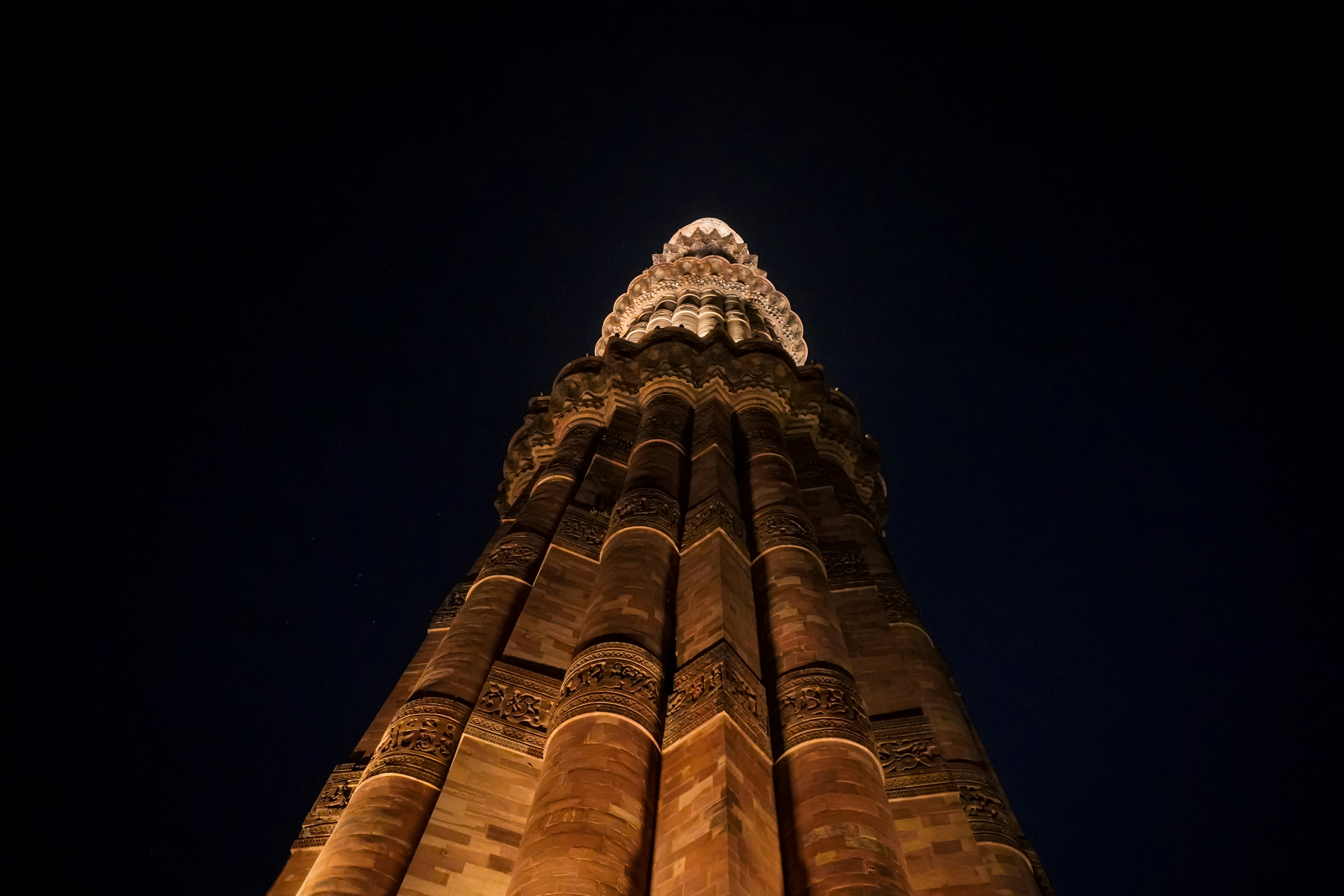 The Qutub Minar tower illuminated against a dark night sky in Delhi