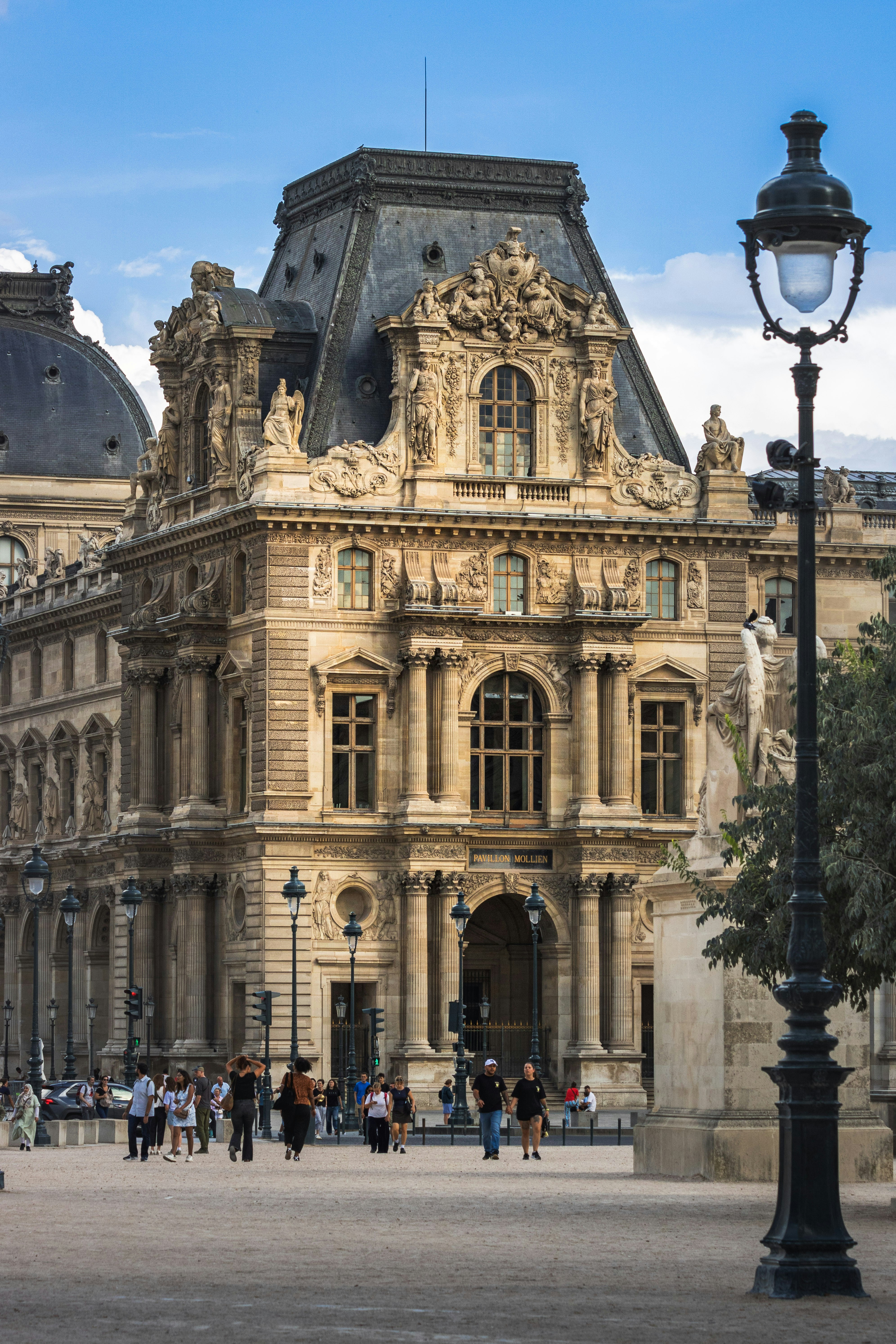 People walking in front of the ornate Pavillon Mollien at the Louvre in Paris