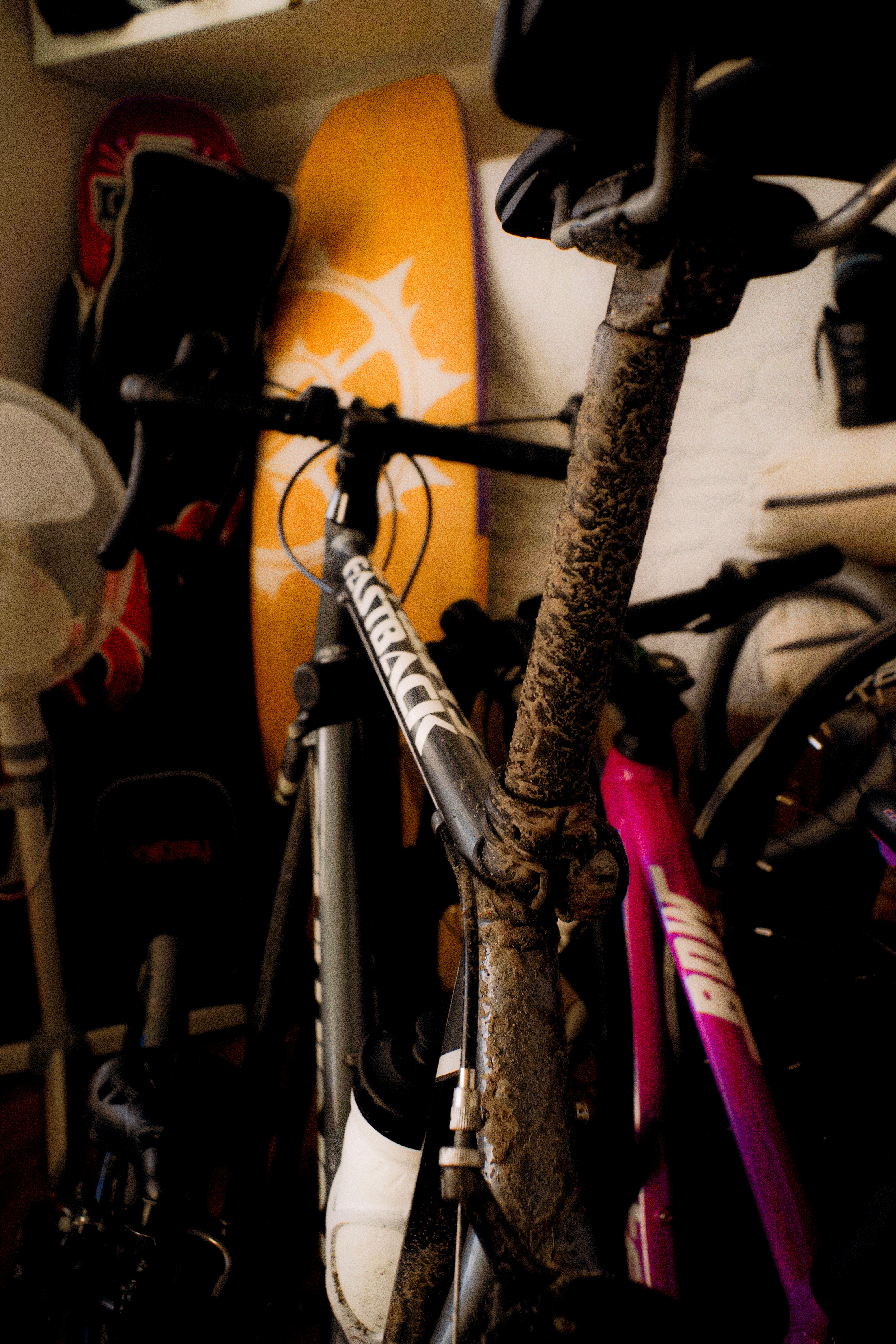 A muddy bicycle frame with a water bottle in a cluttered storage space