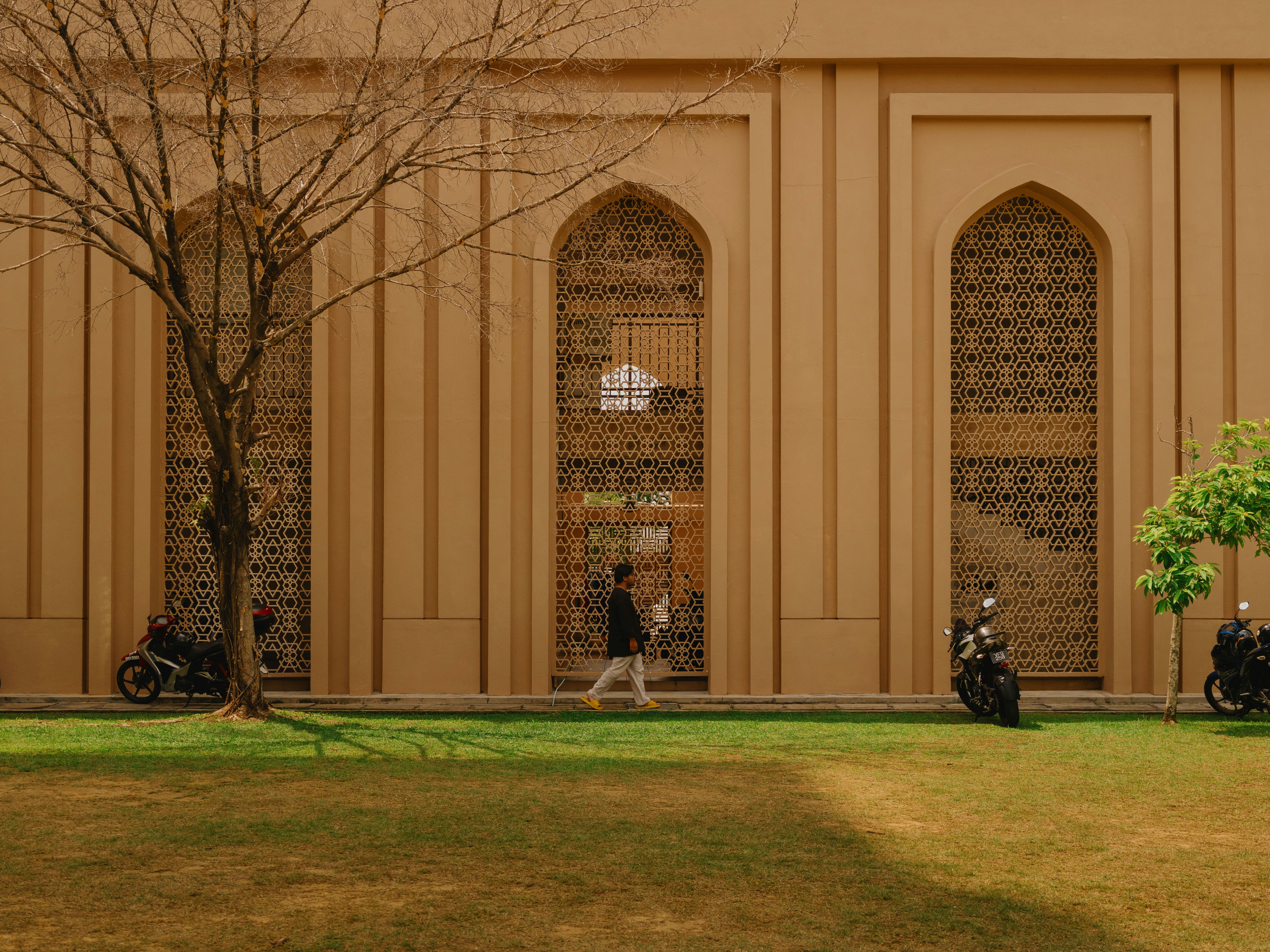 A person walking past the sandstone facade of Masjid Tengku Ampuan in Kuala Lumpur