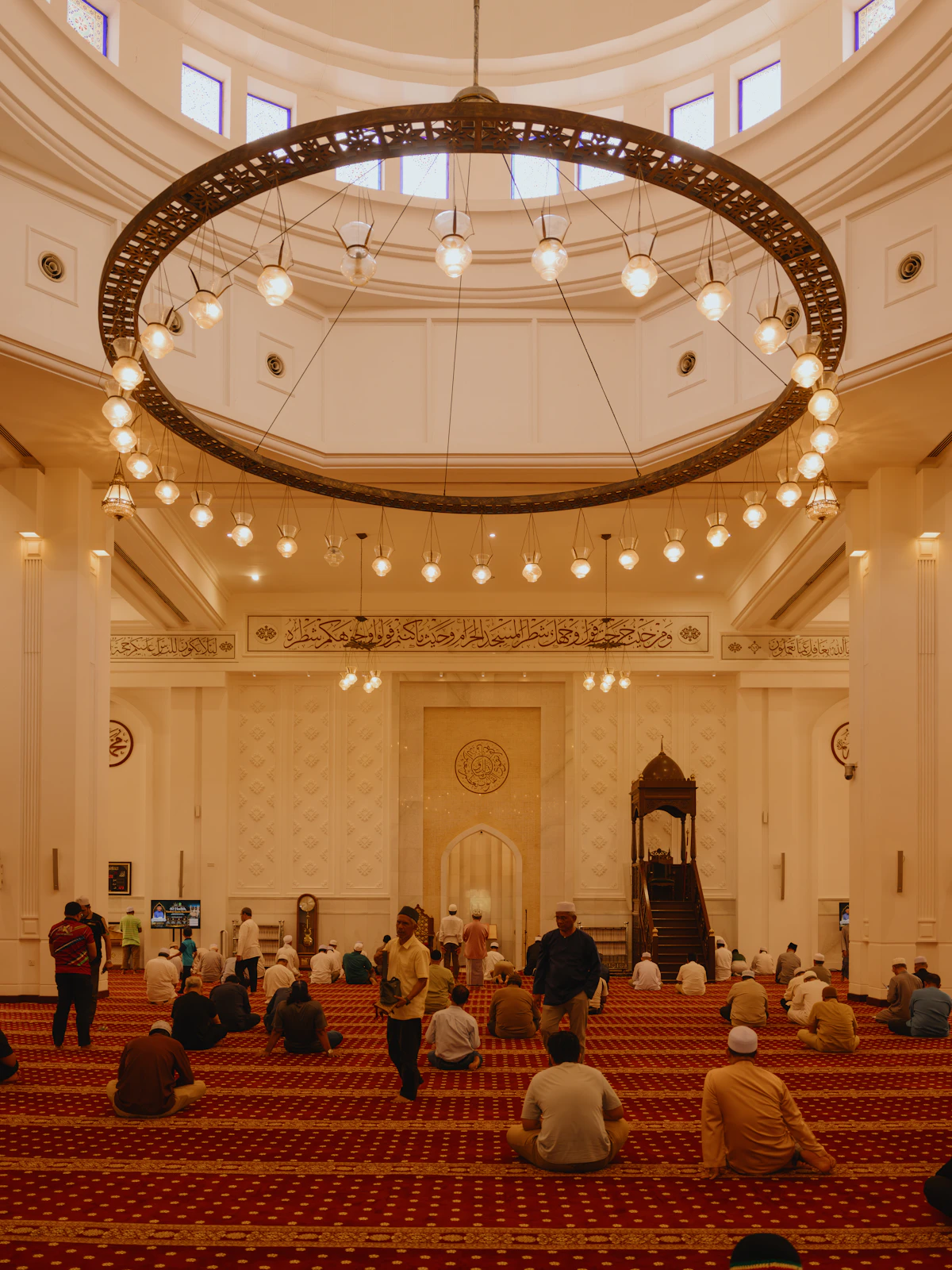Jamaah salat di aula utama masjid dengan lampu gantung bundar