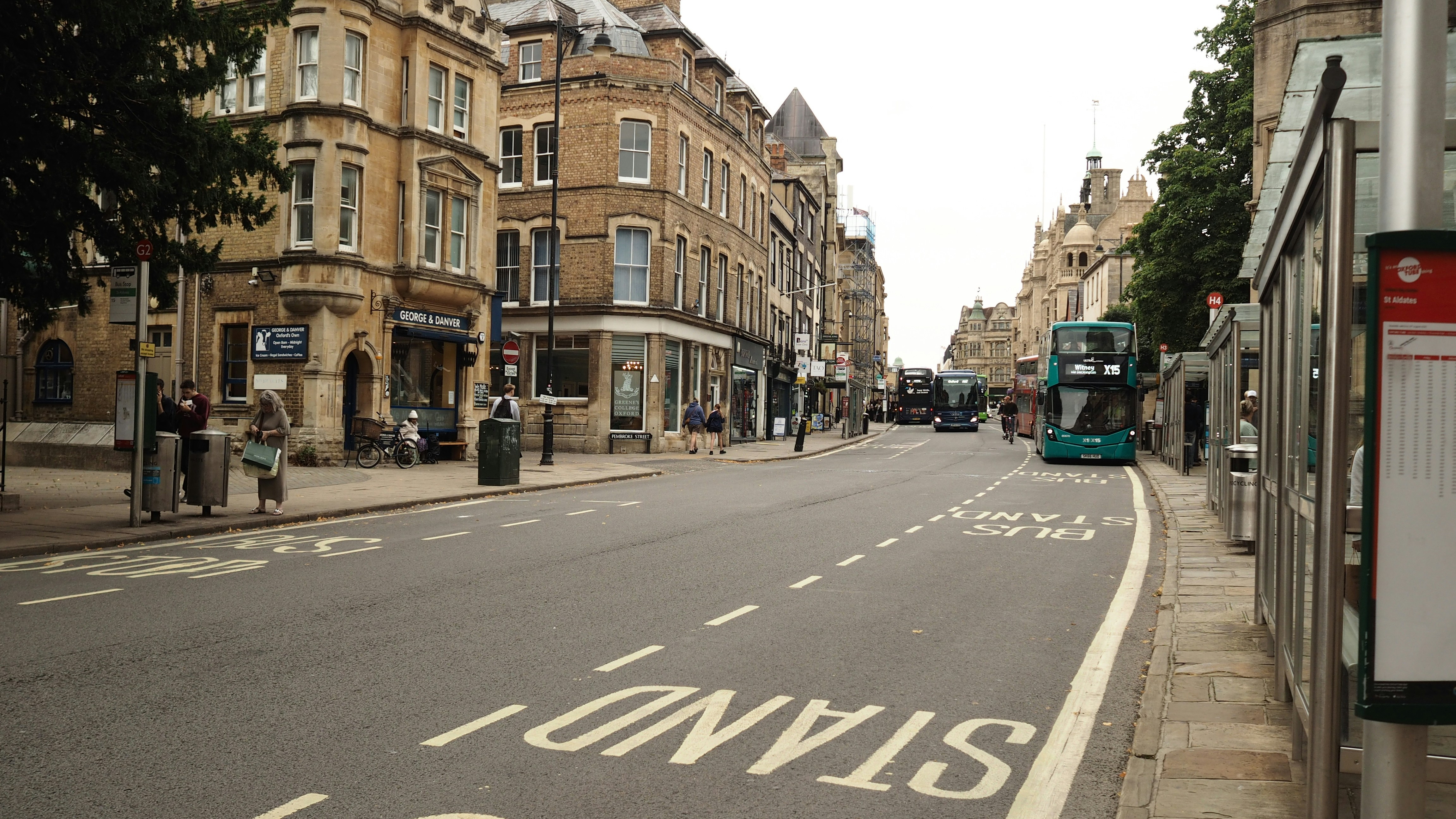 A double-decker bus on a street in Oxford with historic stone buildings