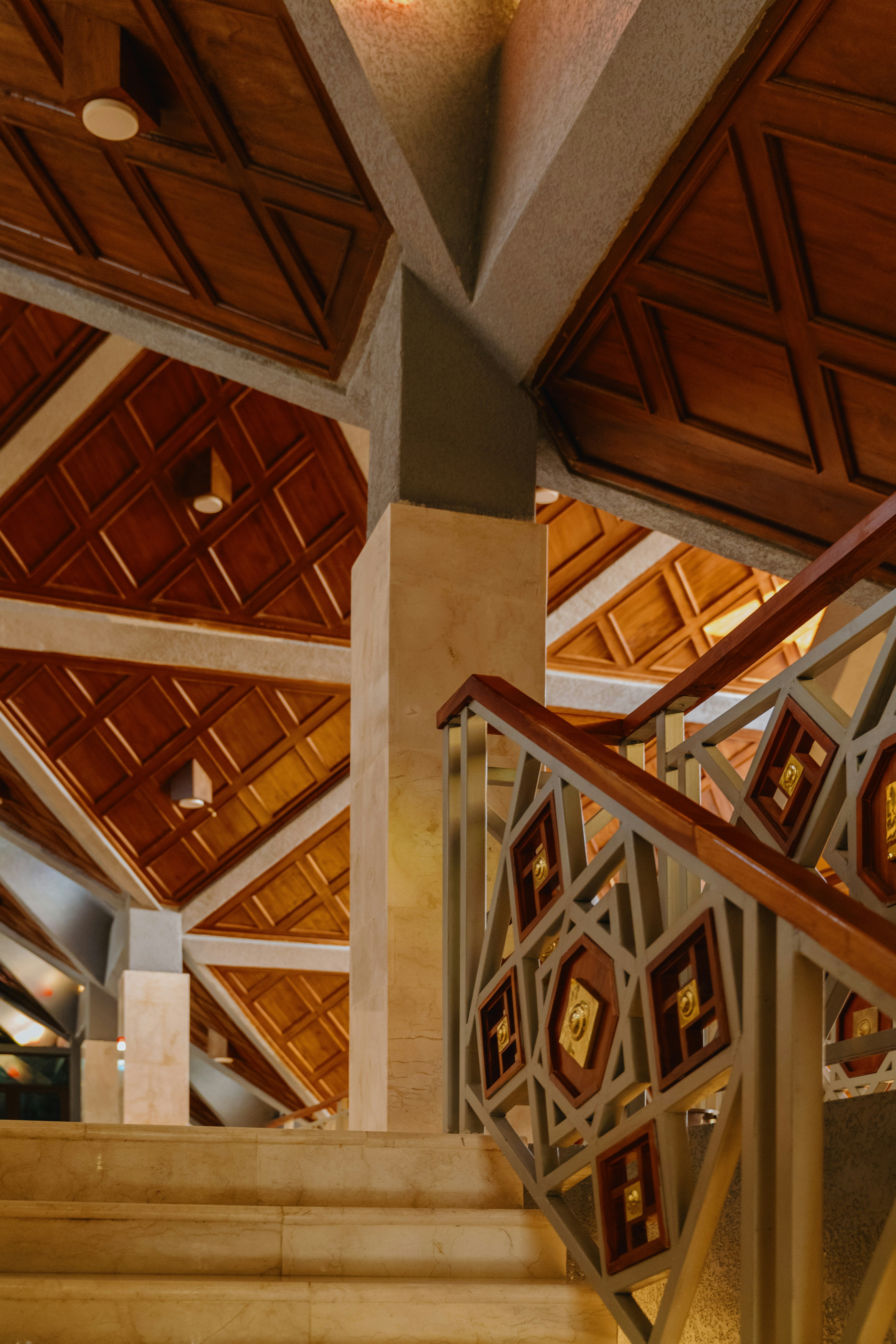 A carved wooden staircase and geometric ceiling detail inside Masjid Nurul Wathon in Bogor