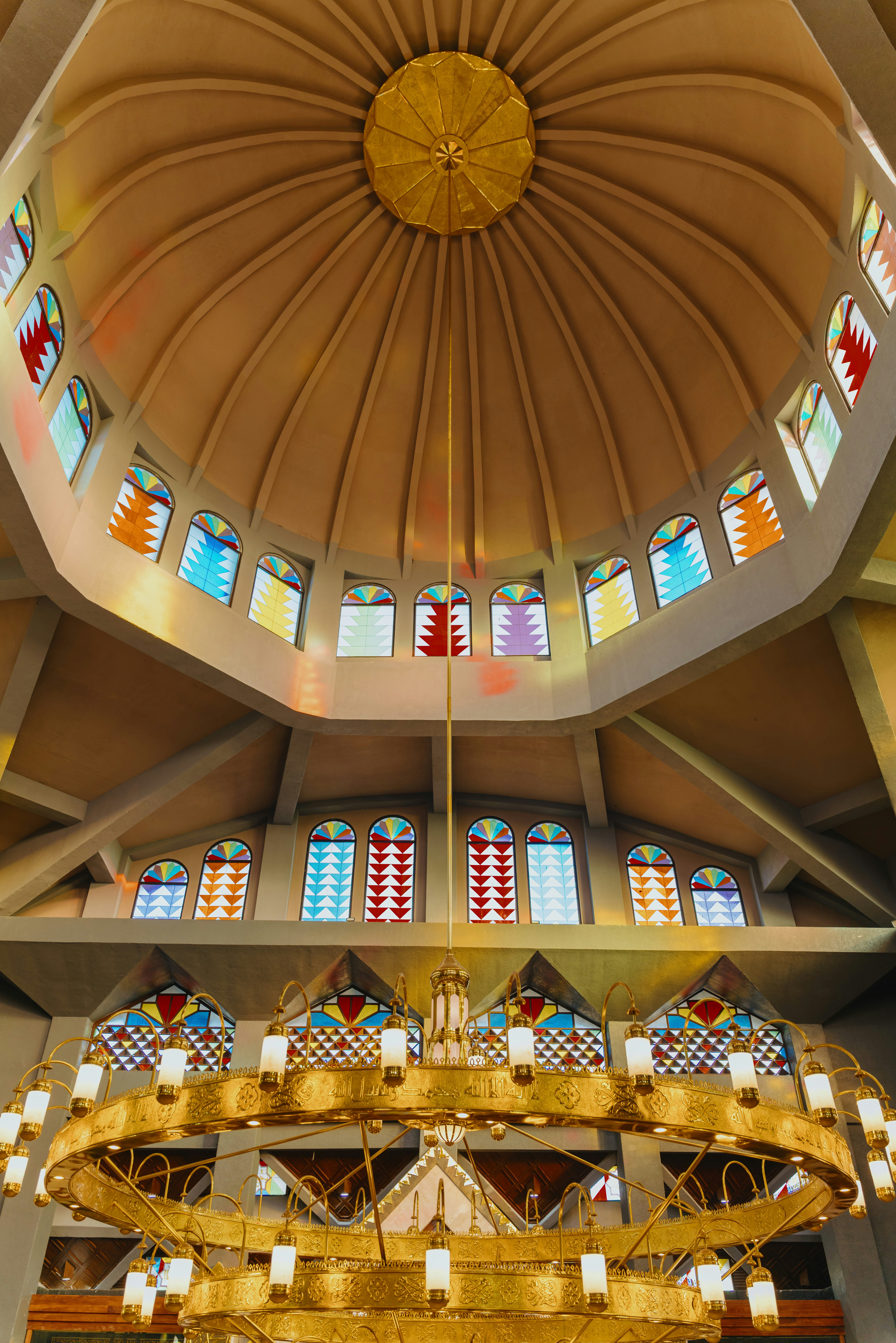 The interior of a dome with stained glass windows and a large gold chandelier