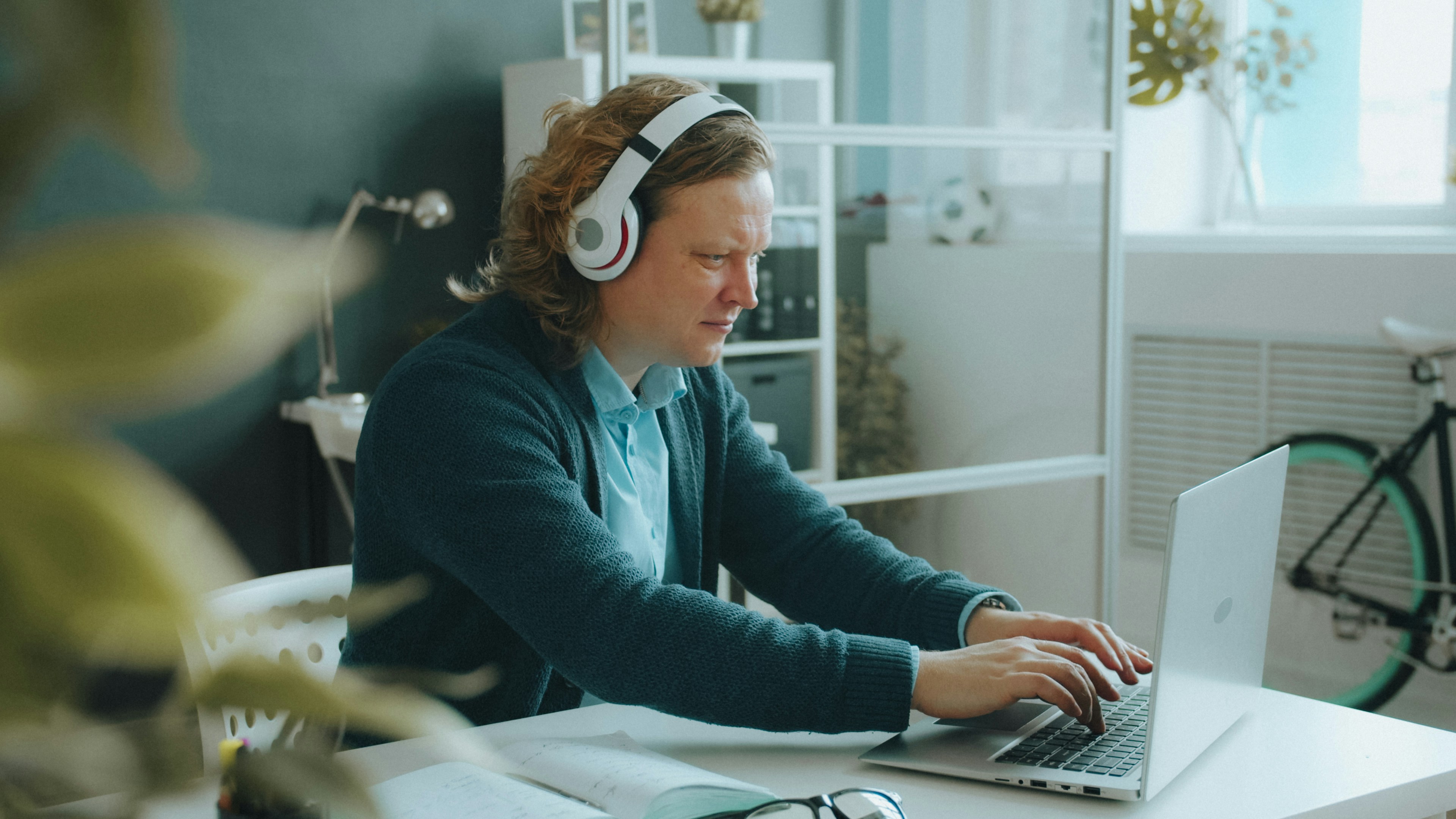 A support specialist wearing headphones and typing on a laptop at home