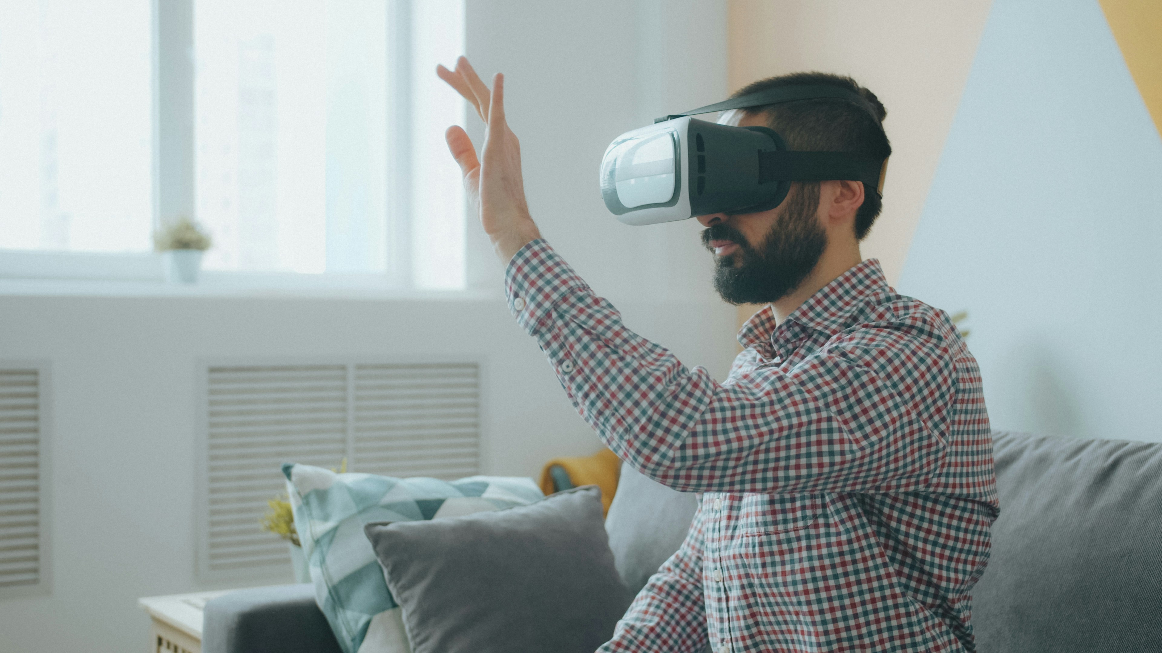 Un uomo con una camicia a quadri che indossa un visore di realtà virtuale su un divano