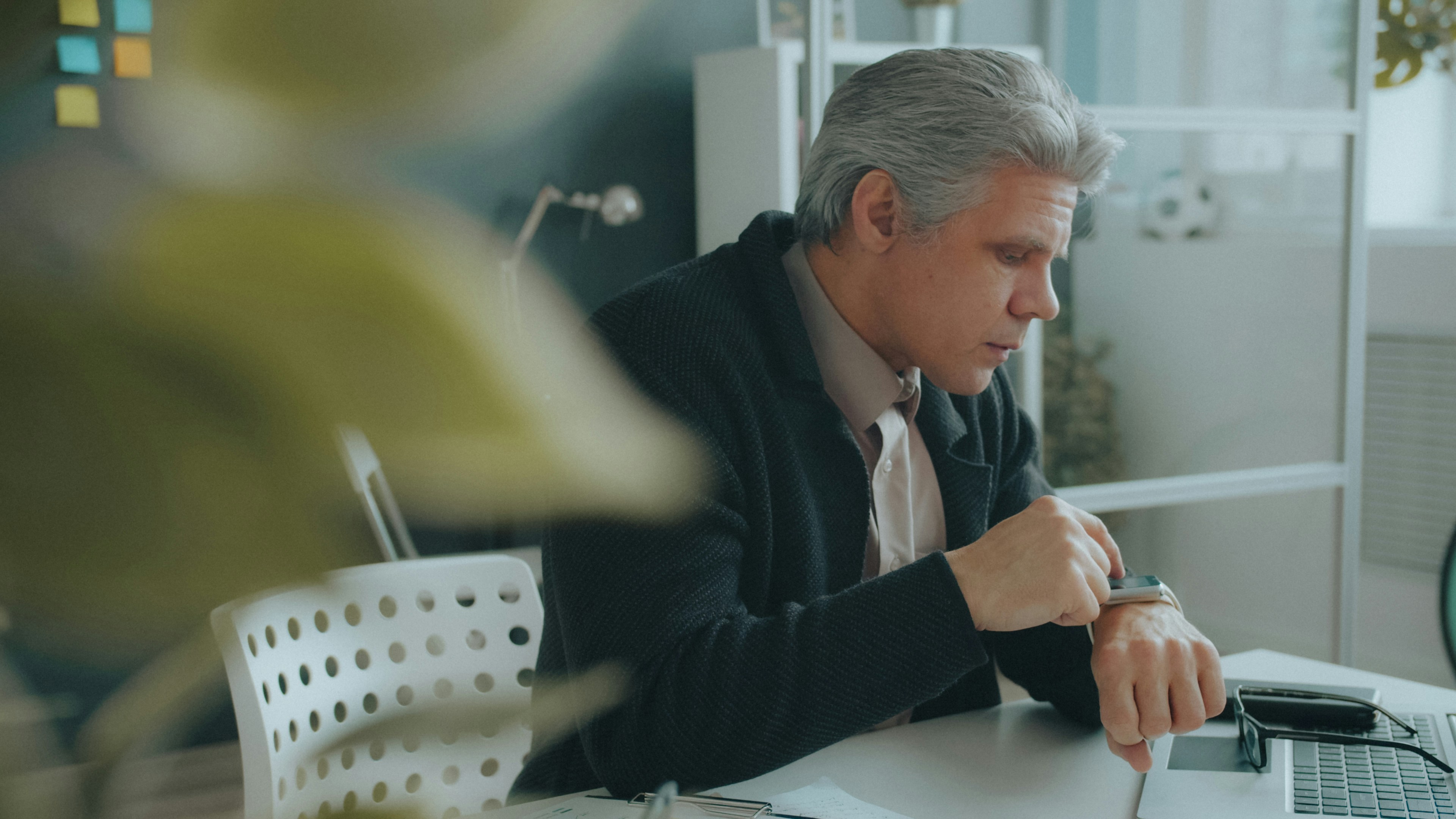 Business leader checking his watch at his desk, deciding where his best hours go with Pareto principle productivity