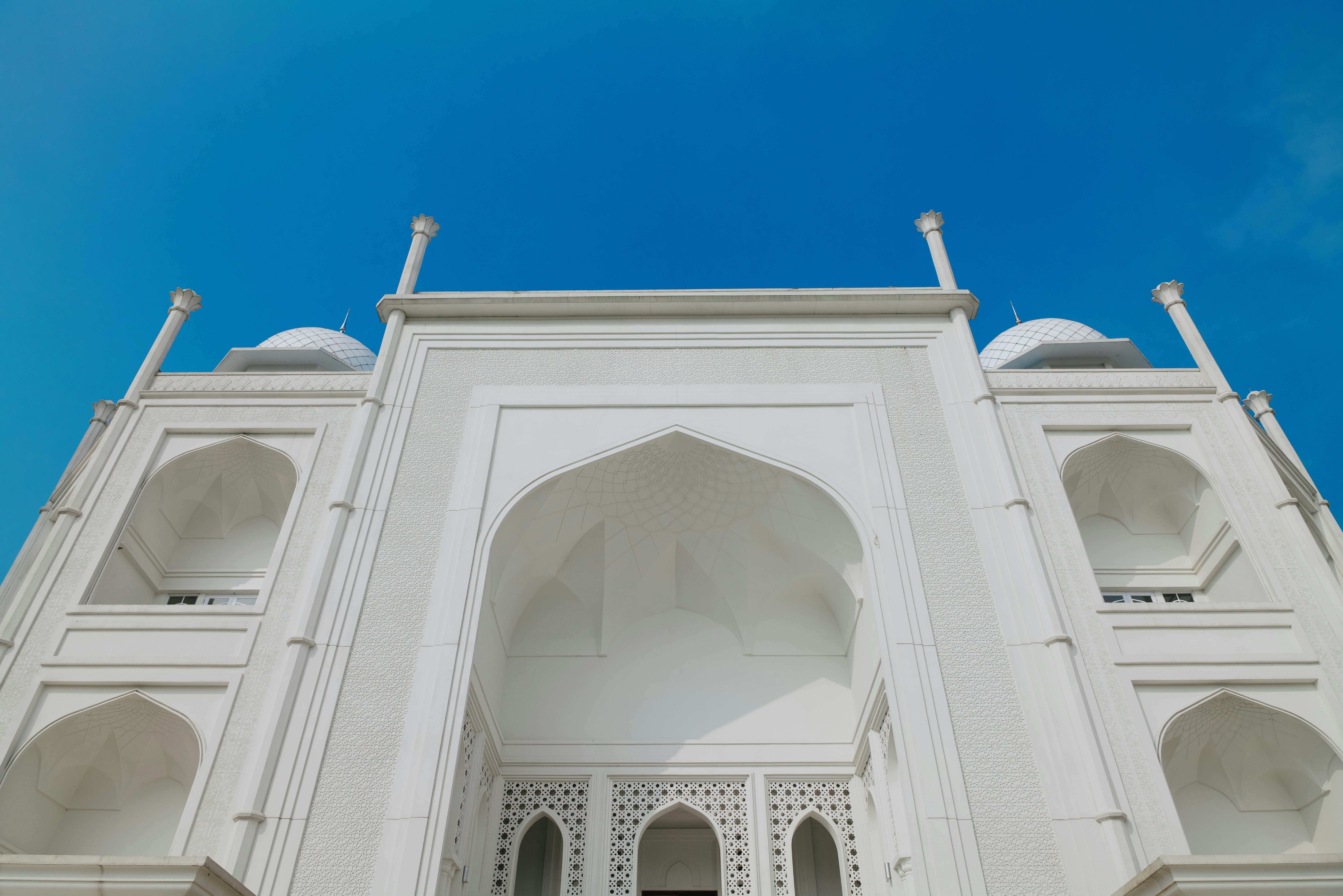 L'ingresso ad arco bianco della Masjid Budi Guna contro un cielo azzurro limpido