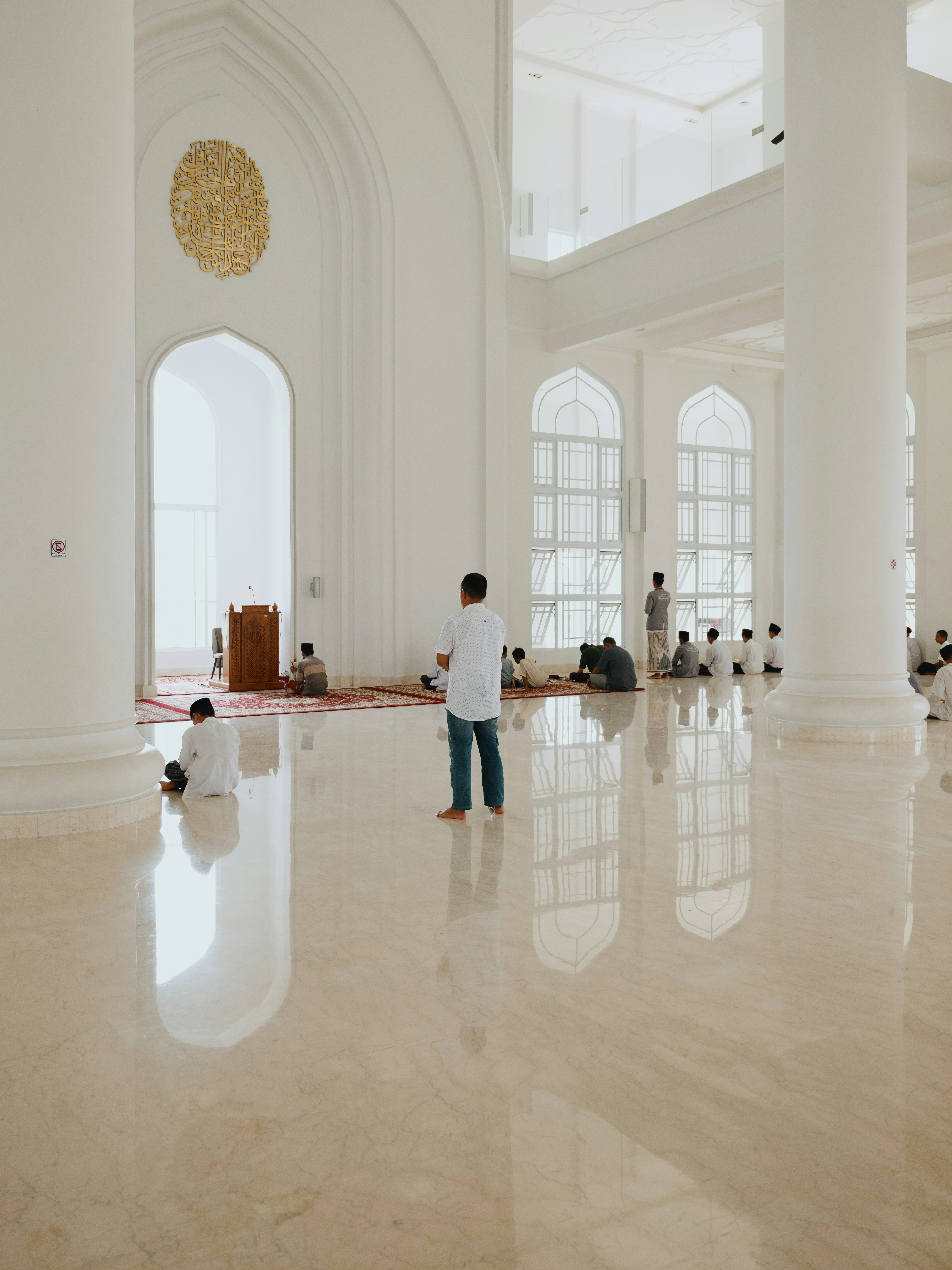 Persone in un interno di moschea bianca e brillante con pavimenti in marmo lucido e alte colonne