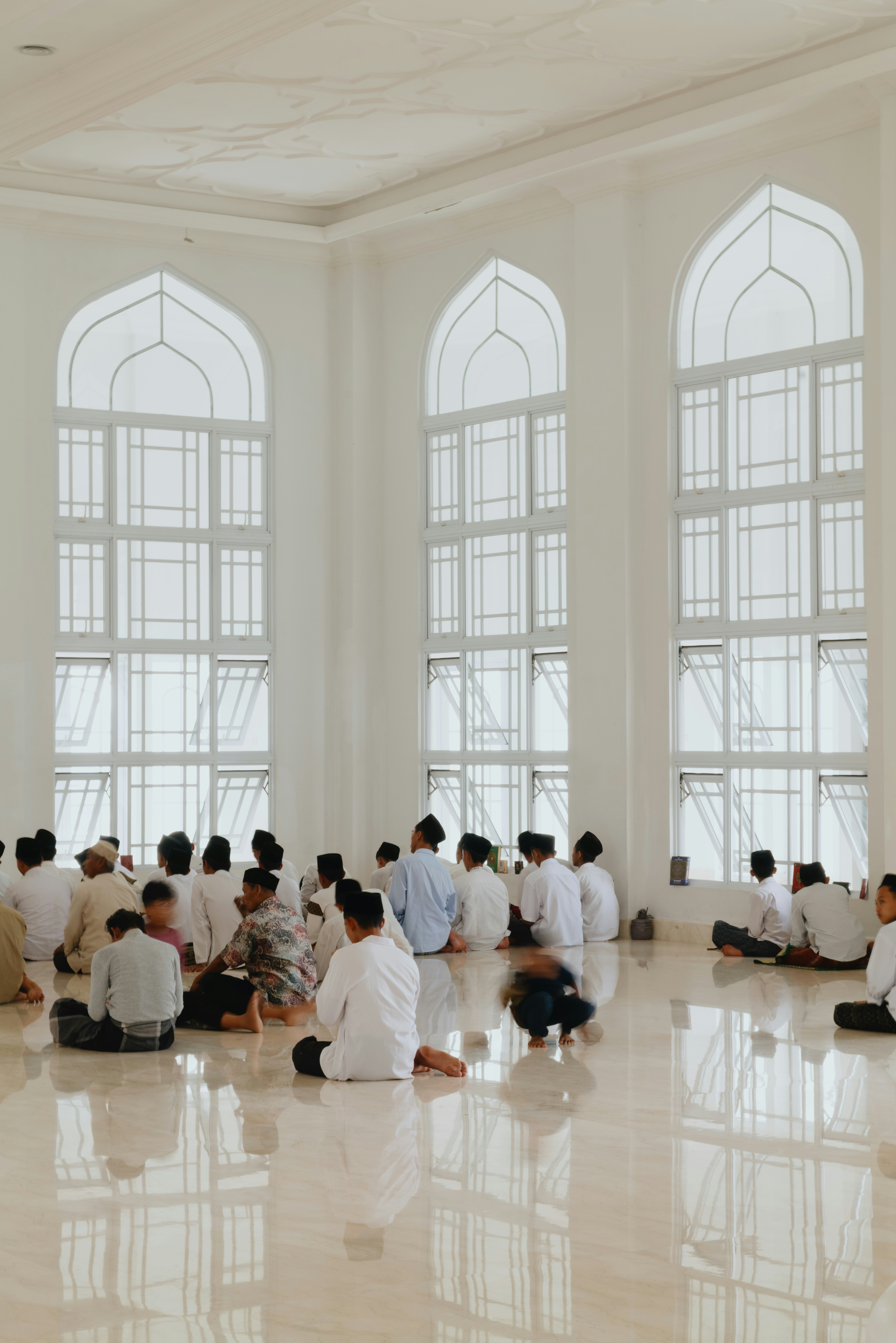 Un gruppo di persone in camicie bianche sul pavimento della Masjid Budi Guna