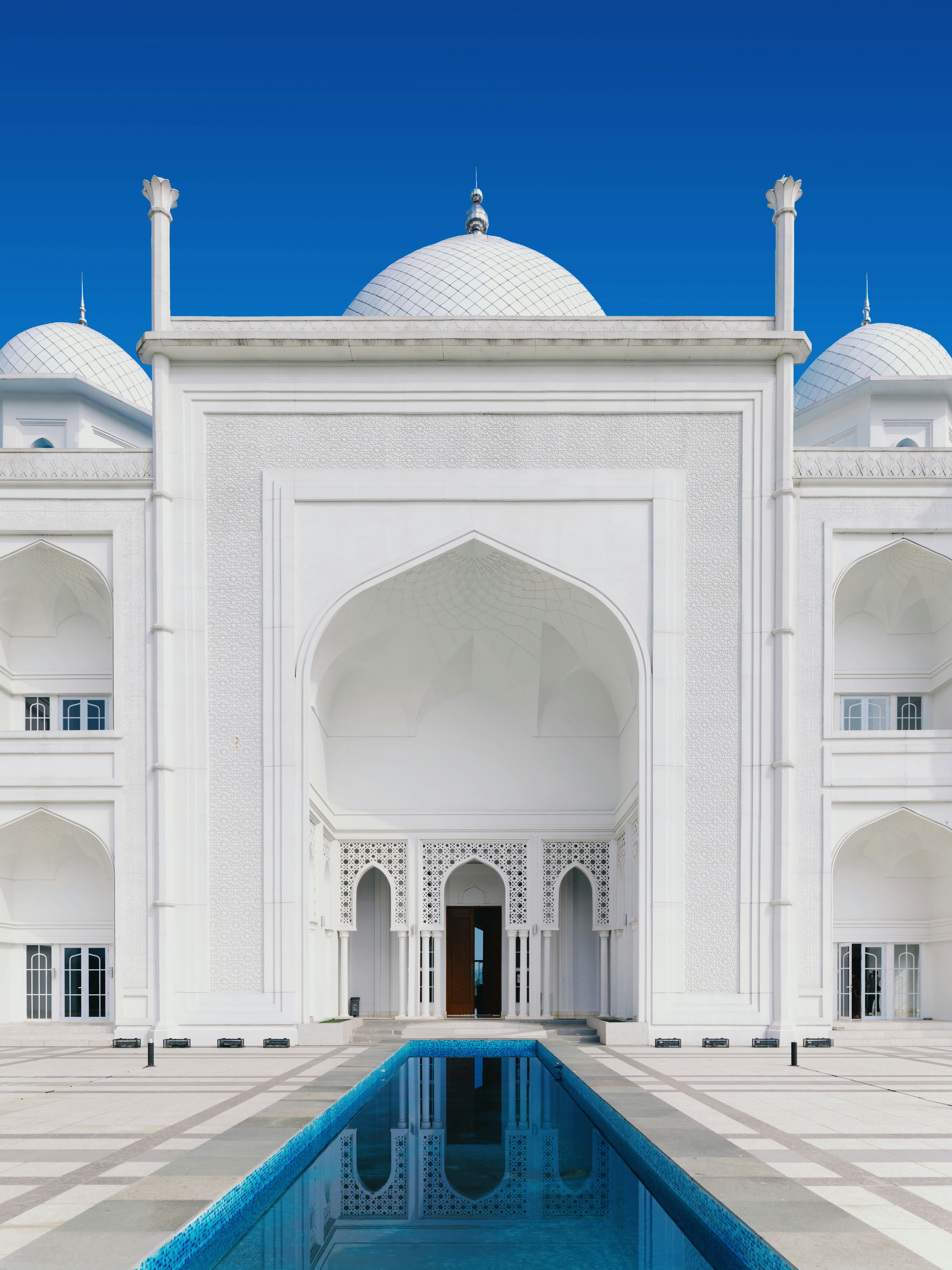 La facciata bianca della Masjid Budi Guna a Bogor con una lunga piscina riflettente