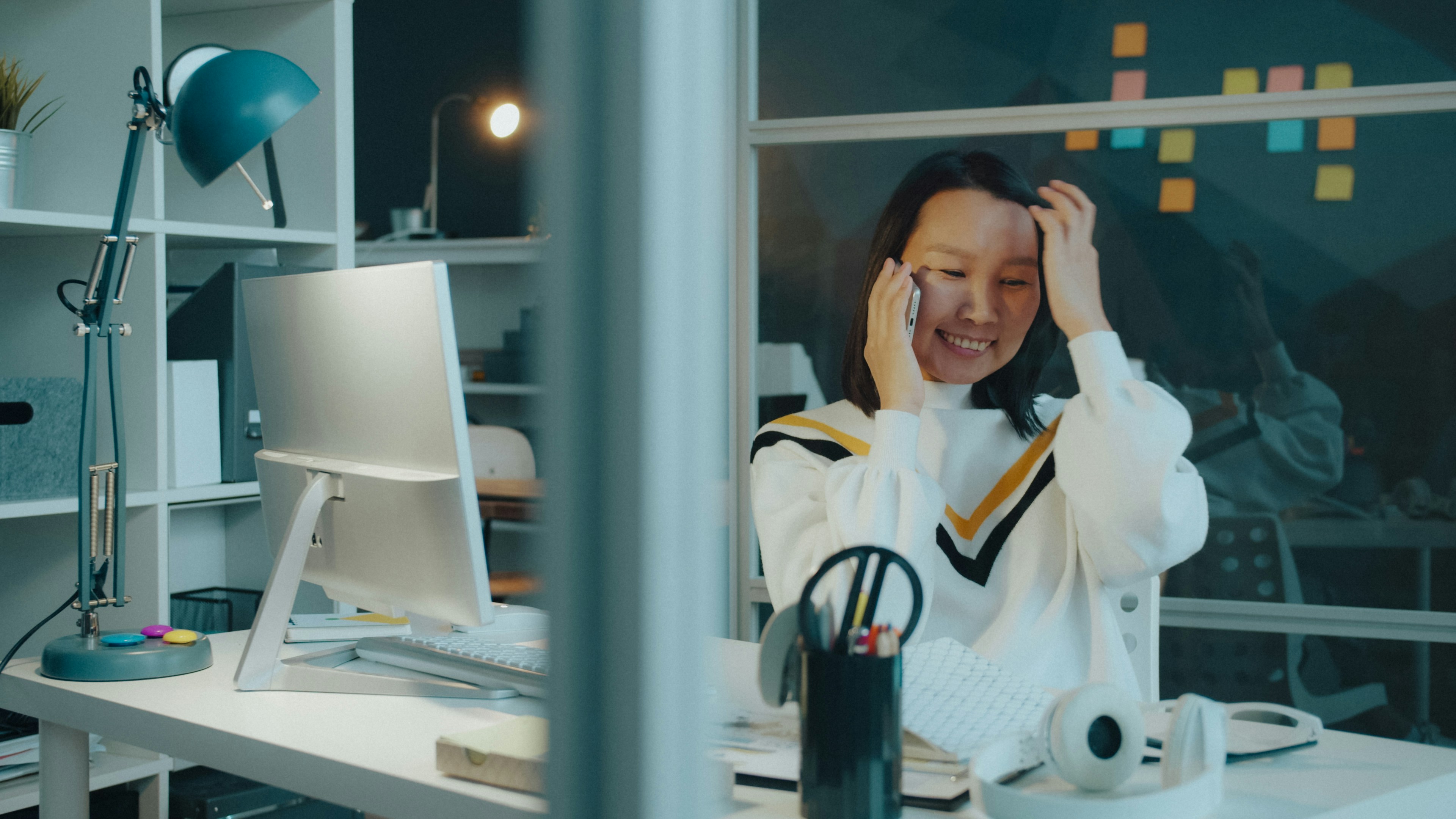 Mulher conversando ao telefone sentada em sua mesa de trabalho
