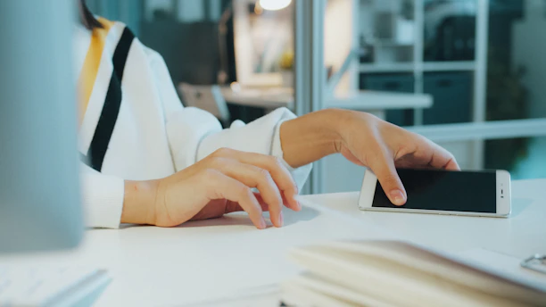 Mãos consultando um smartphone para responder clientes com clareza.