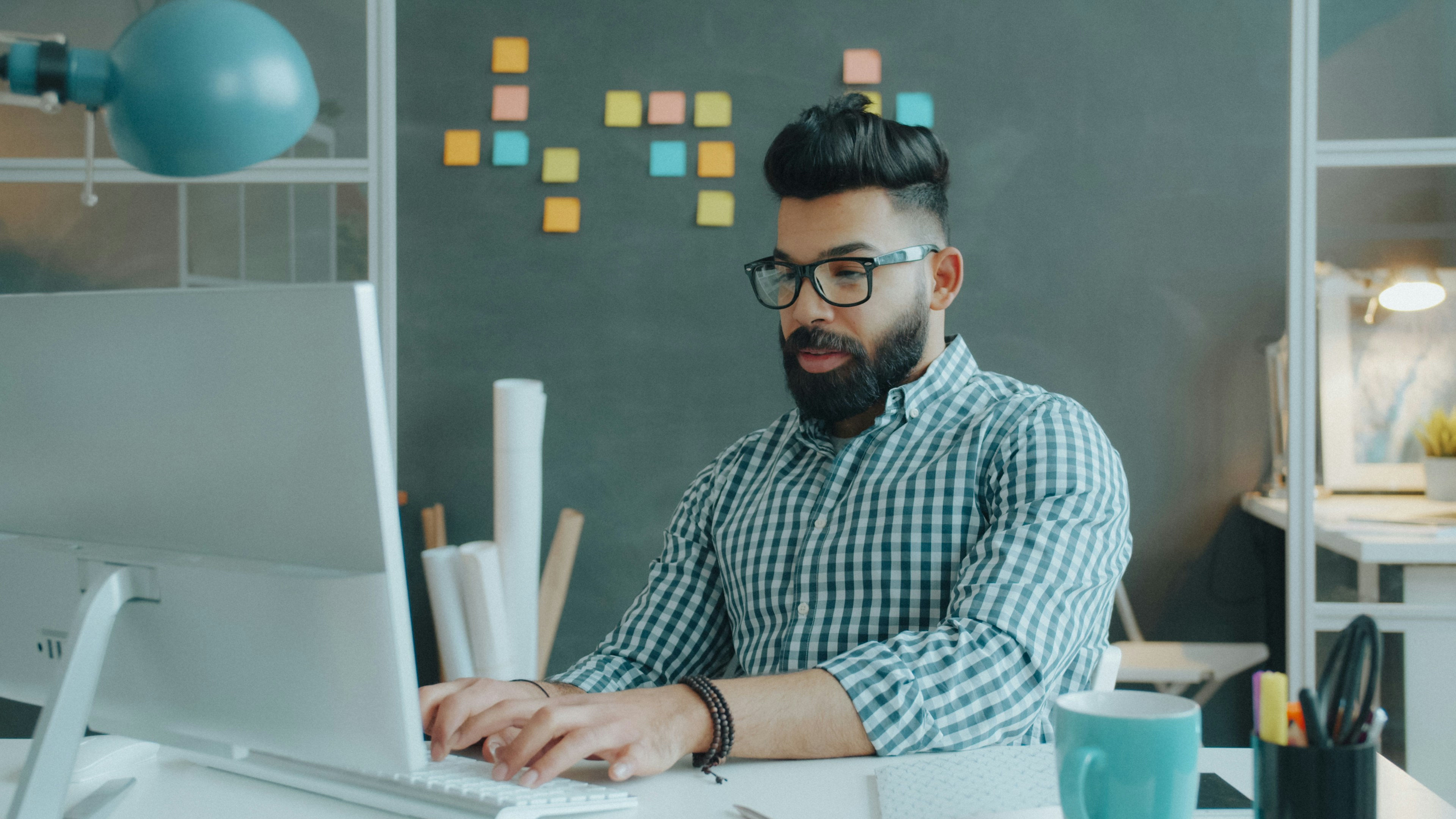 An entrepreneur working at his desk beside a wall of planning notes