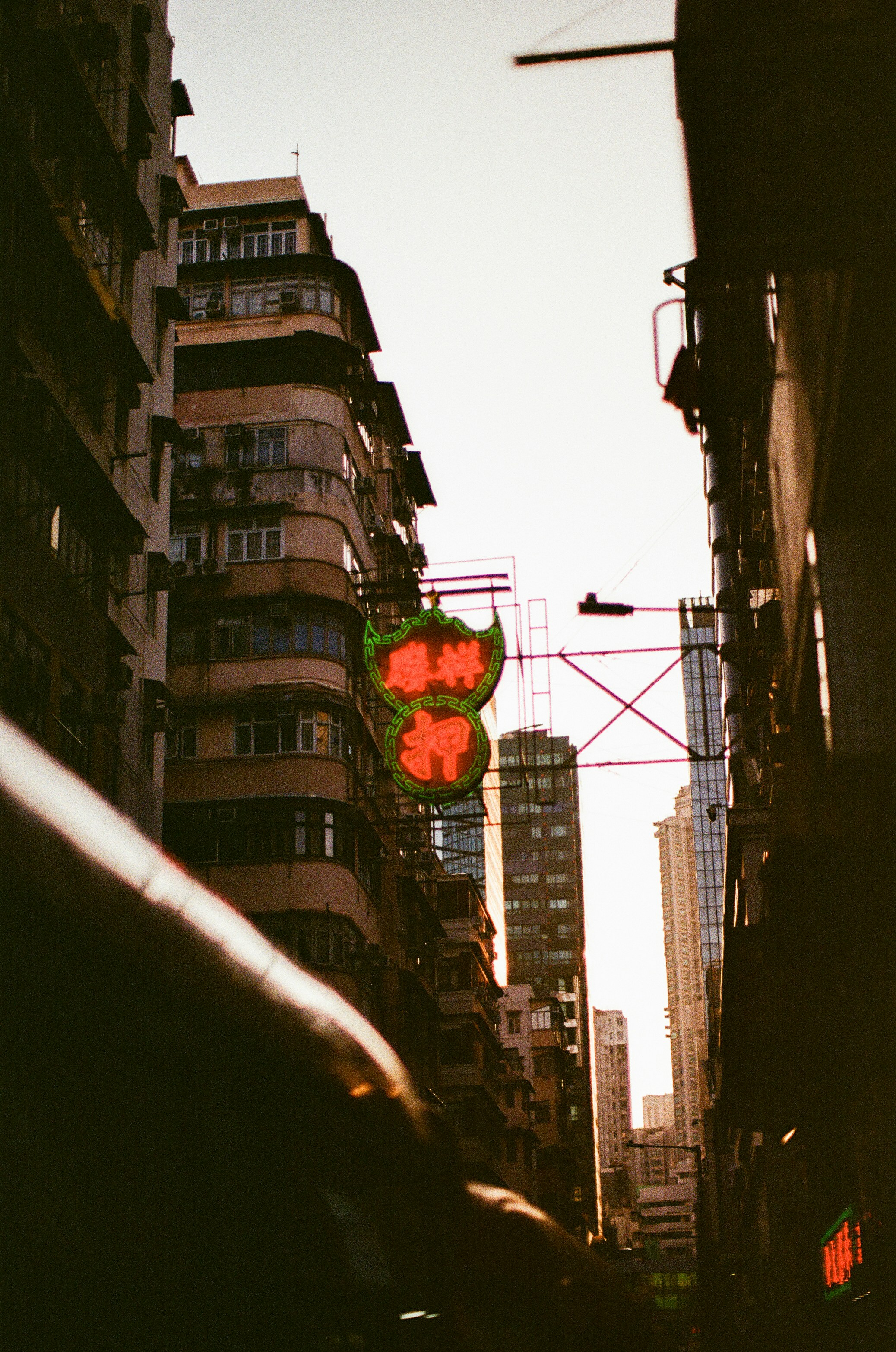 A glowing red neon sign hanging between tall residential buildings in Hong Kong
