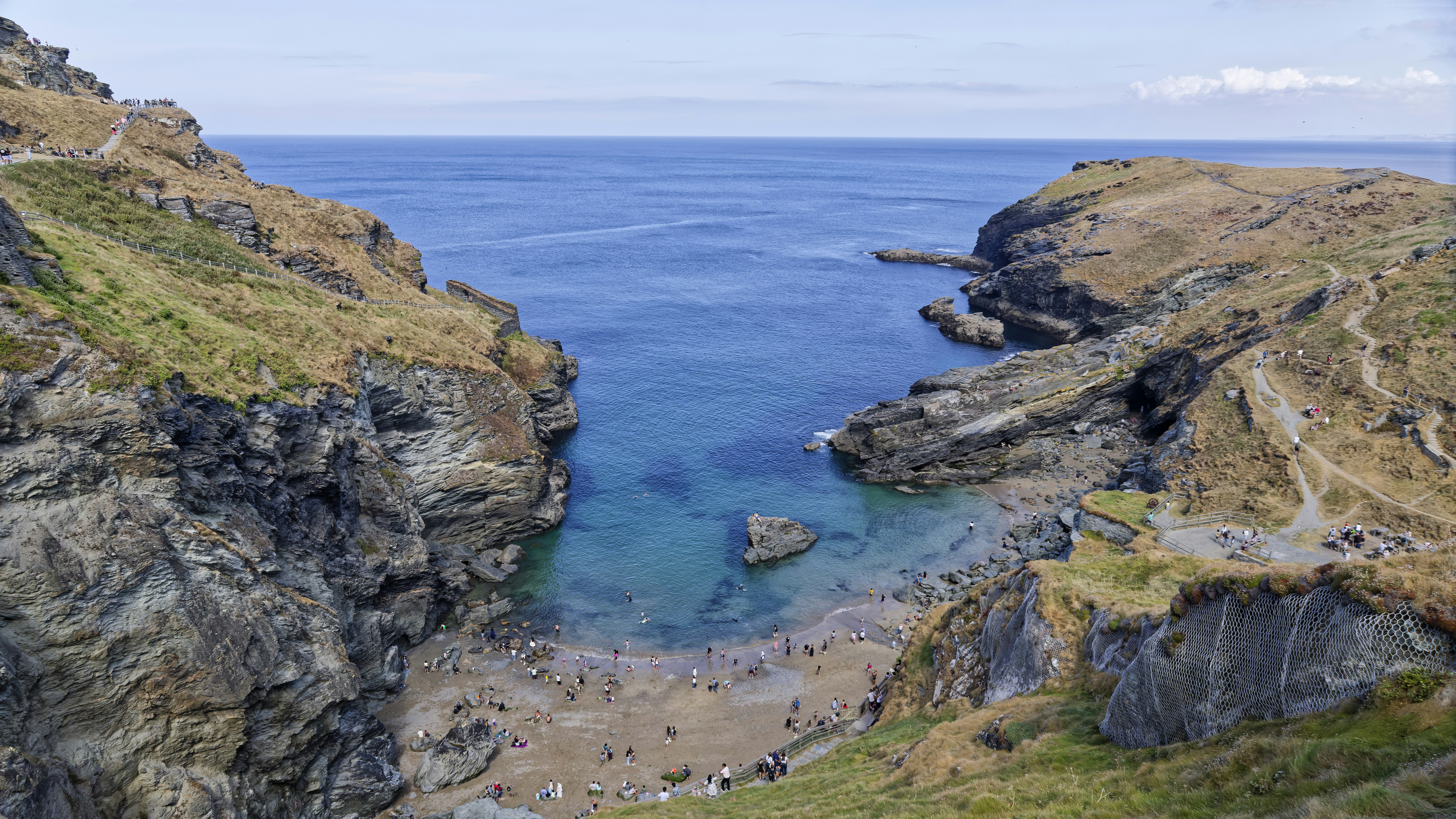 People on a sandy beach nestled between steep rocky cliffs by the ocean