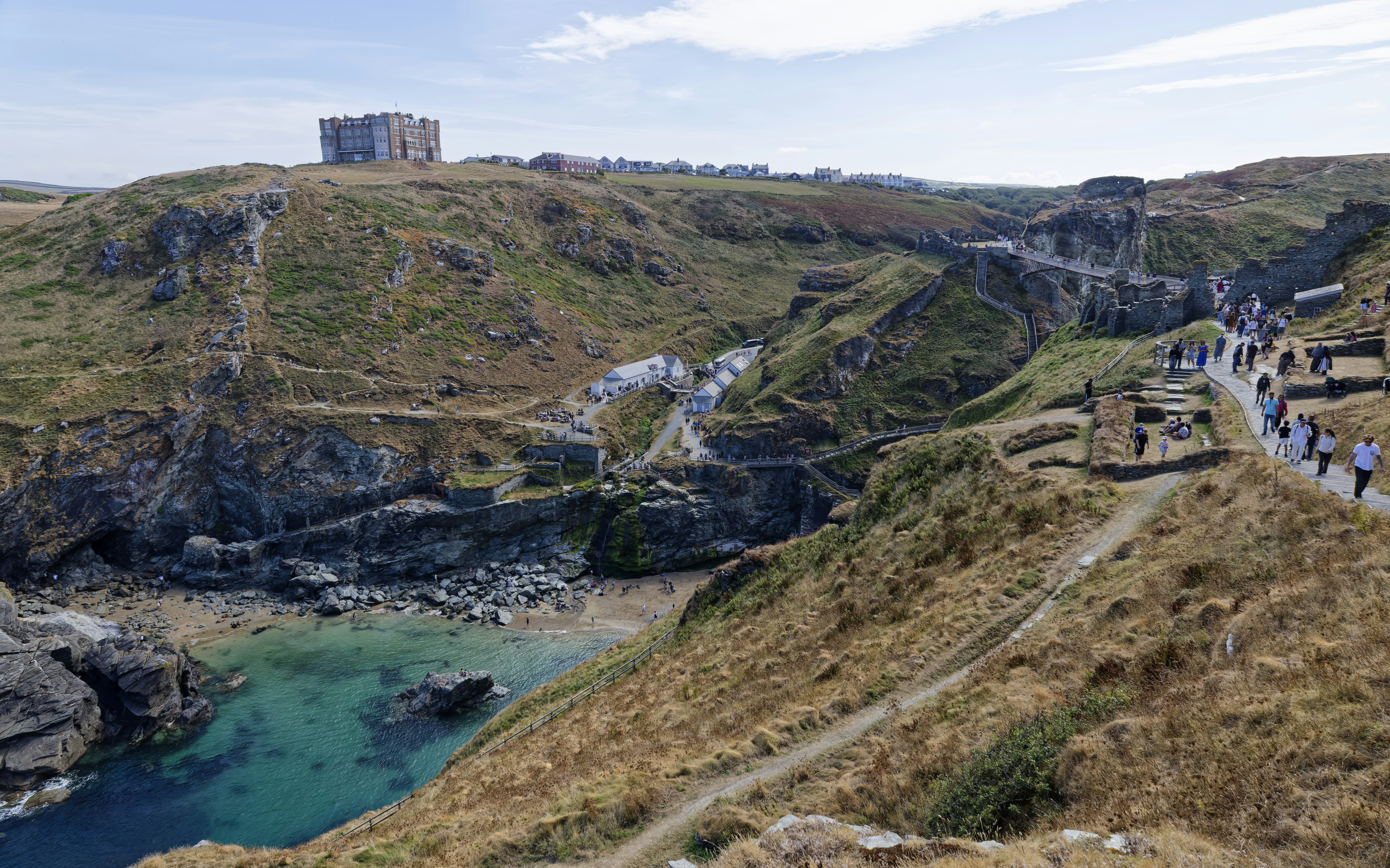 People walking on paths near the ruins of Tintagel Castle in Cornwall