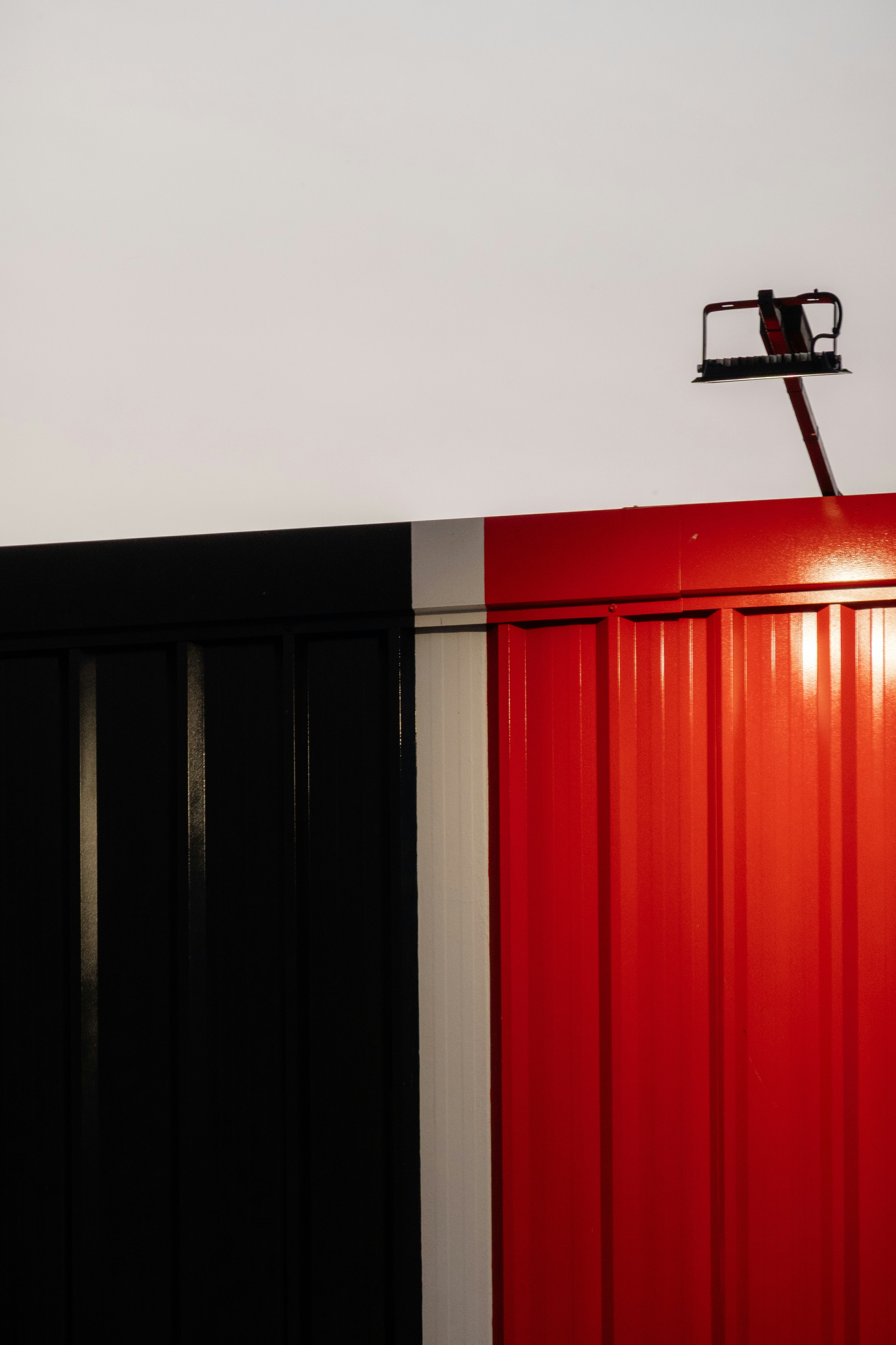 A black, white, and red corrugated metal wall with a small light fixture
