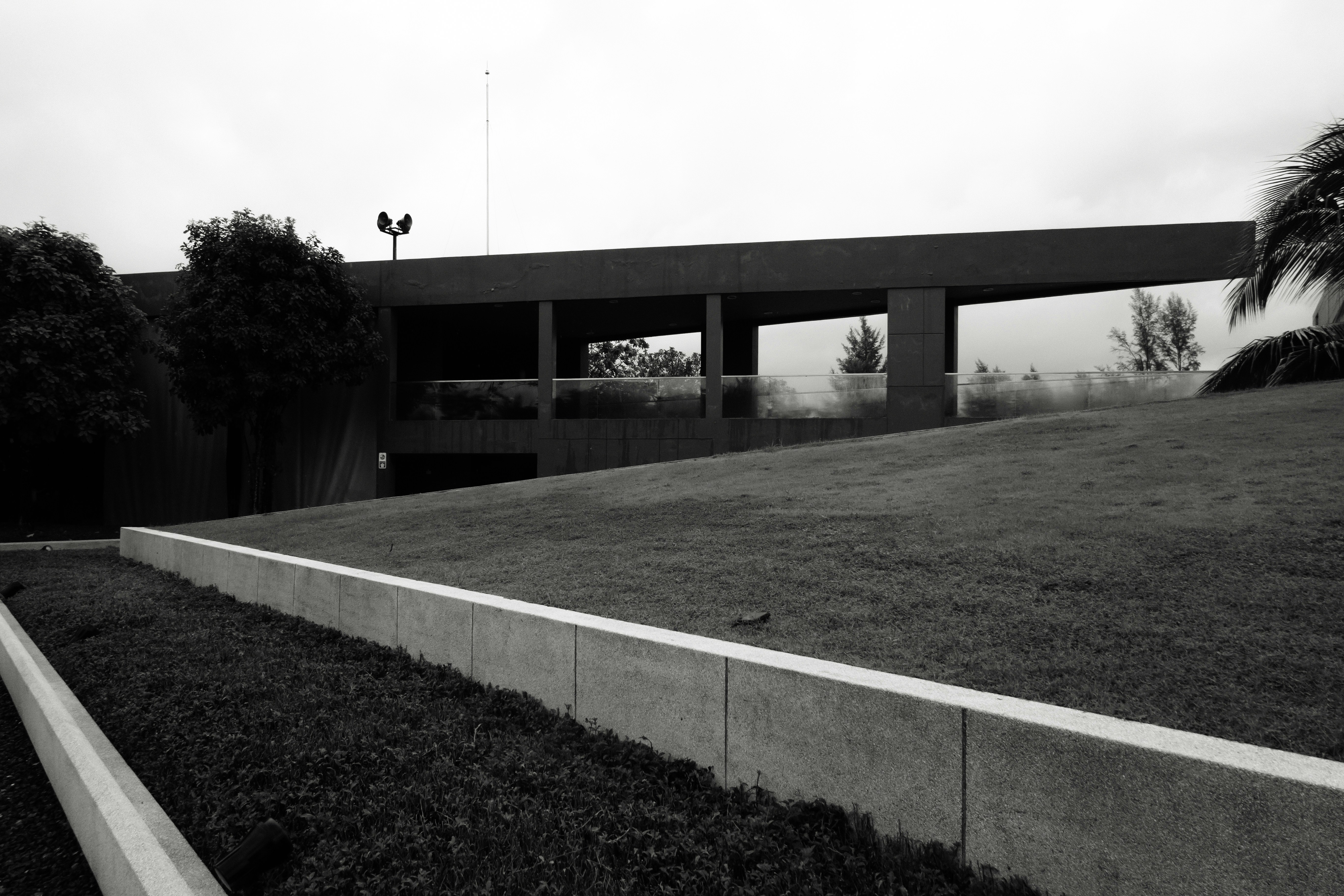 A modern concrete building with a glass balcony overlooking a grassy slope