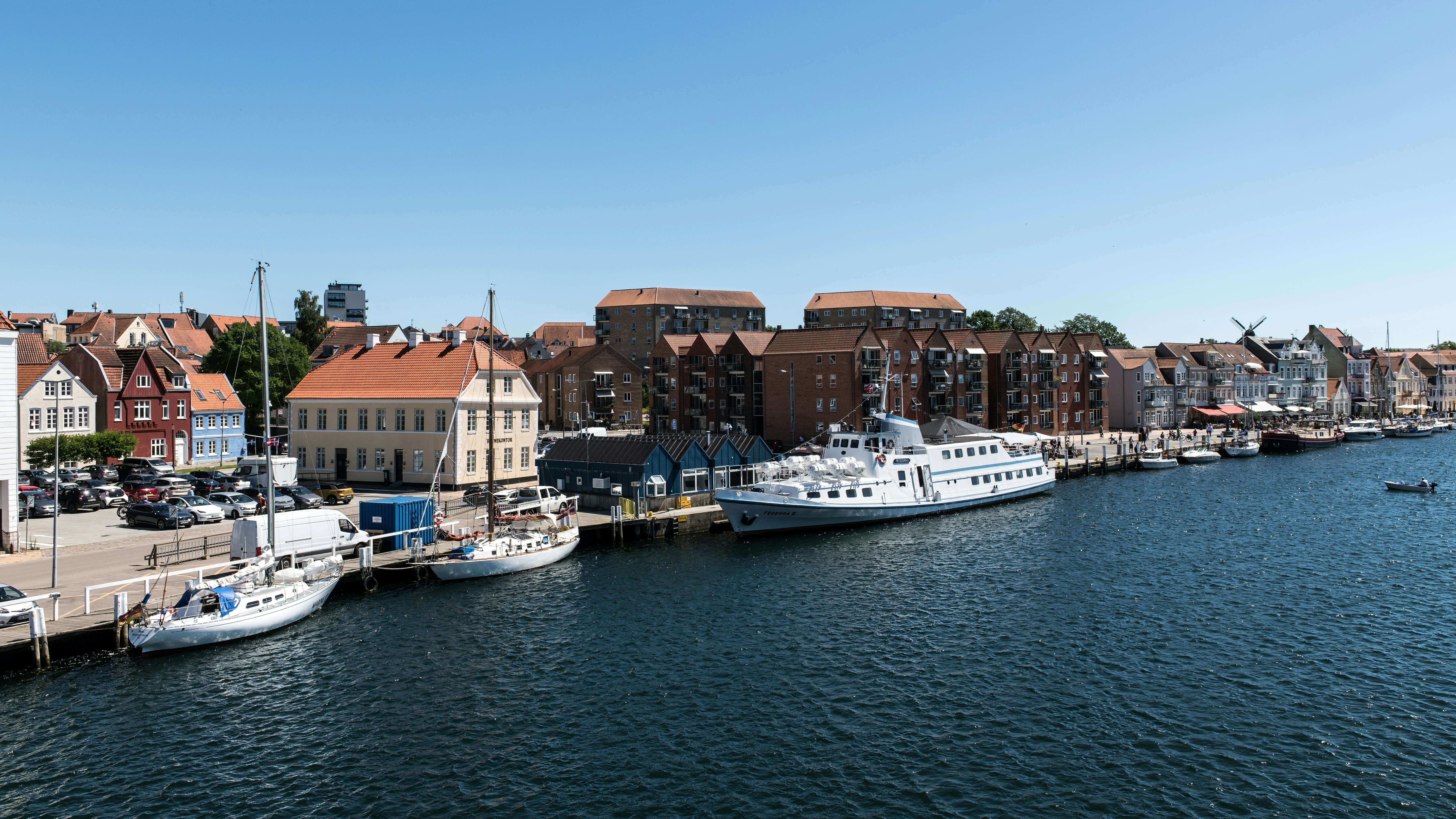 Boats moored at a harbor quay in front of a town with brick buildings