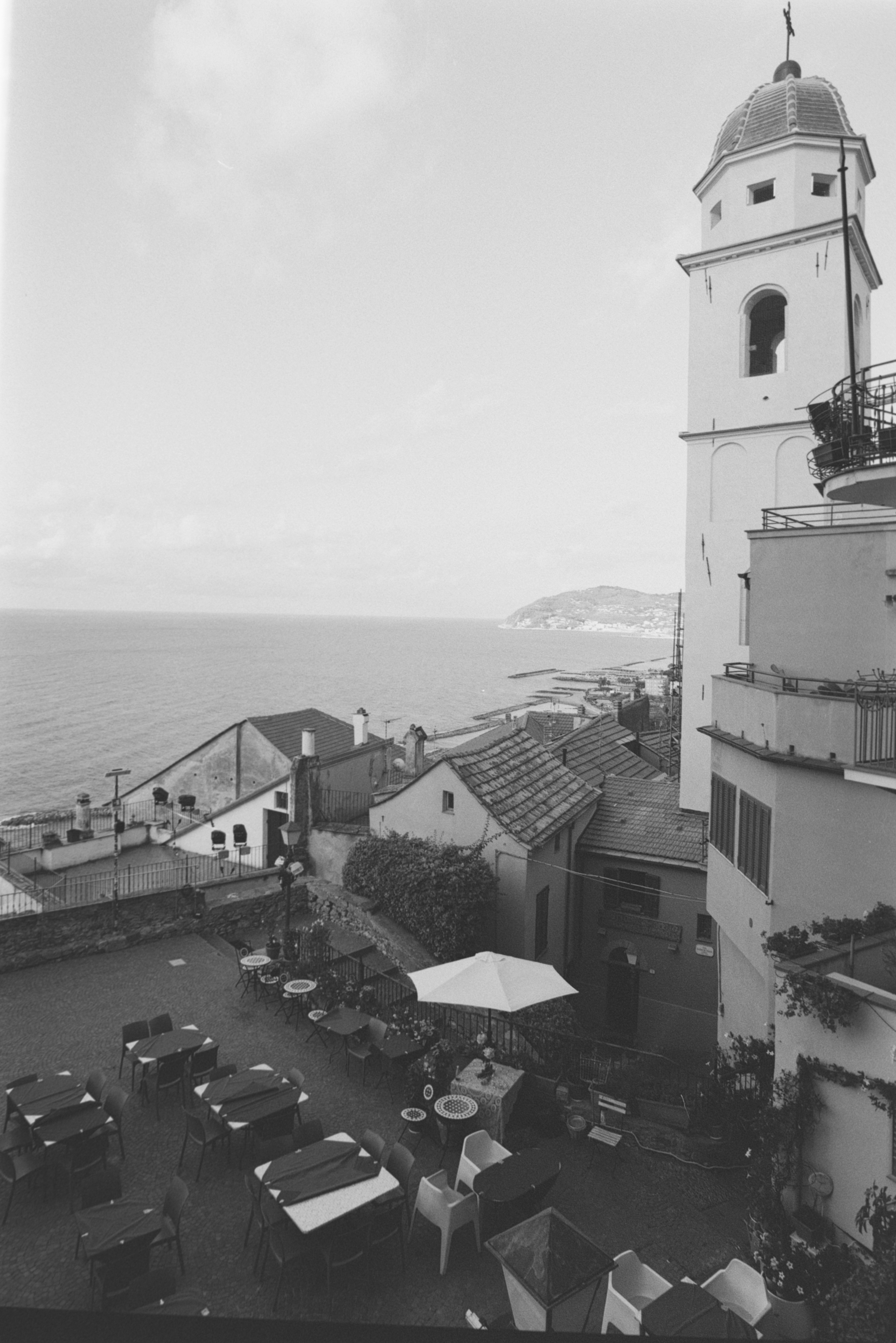 Eine Außenrestaurantterrasse neben einem Glockenturm mit Blick aufs Meer