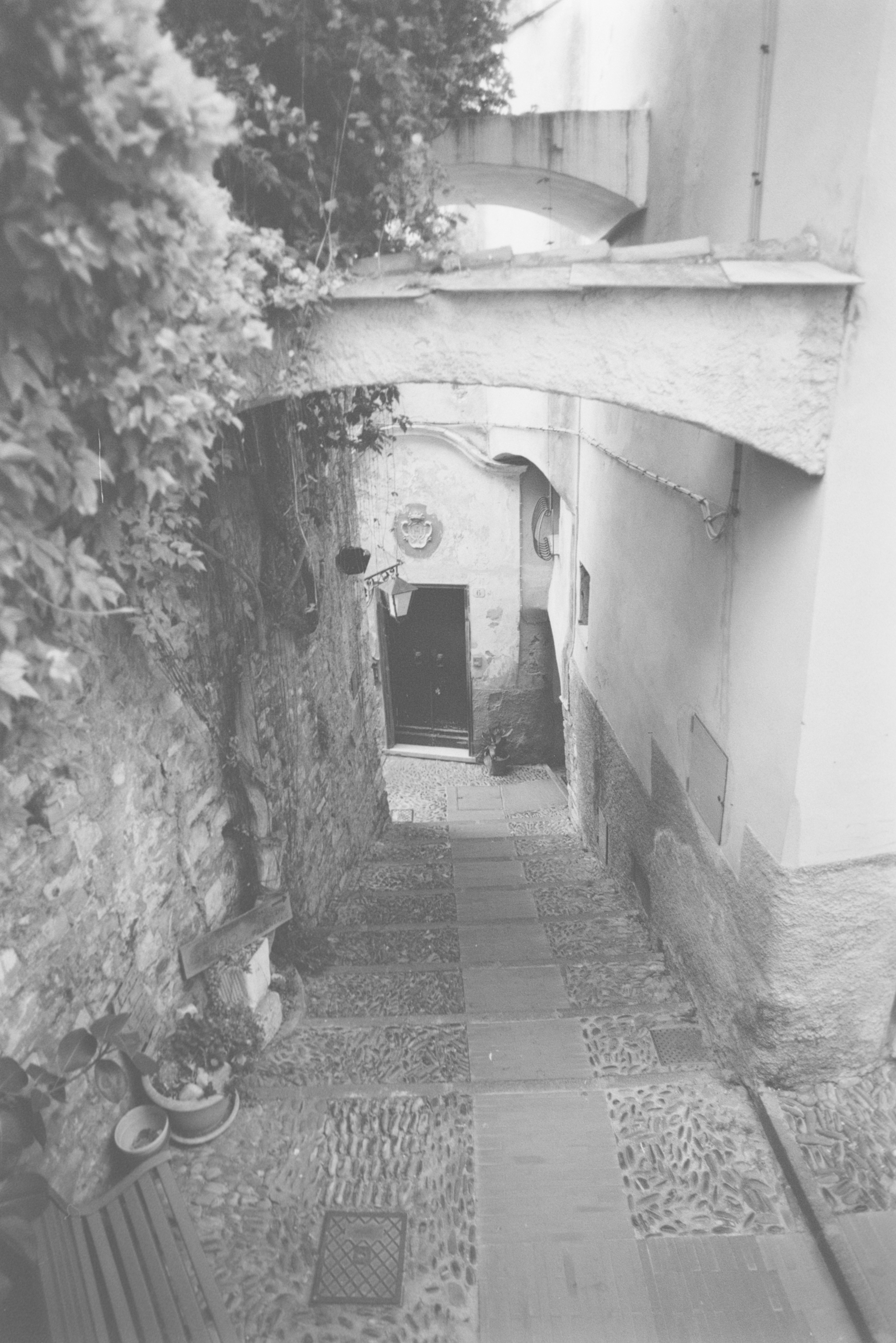 A narrow stone staircase descending between old walls with an arched stone bridge above